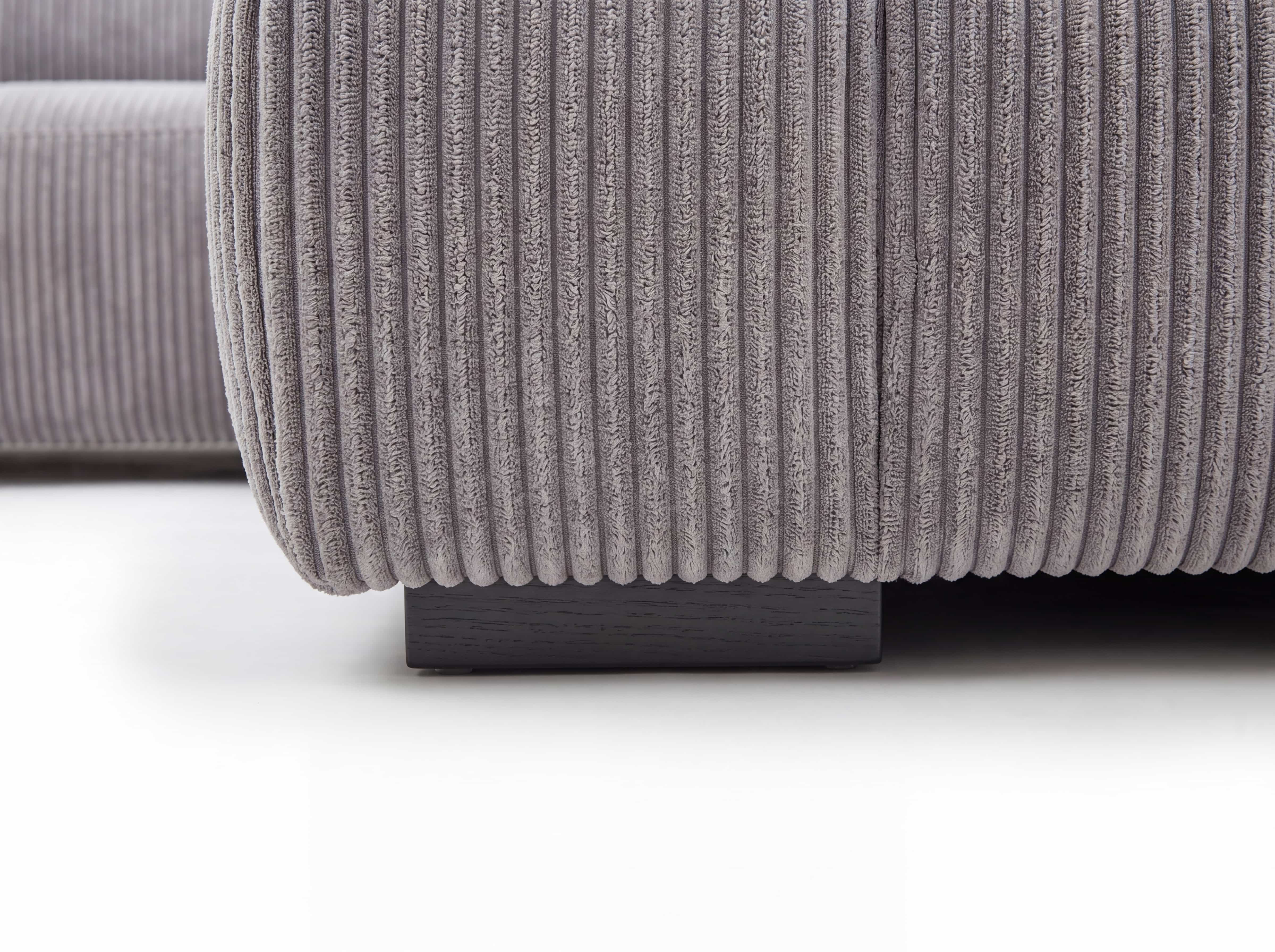 Ecksofa Kazar – Detailansicht des grauen Cordbezugs und dunklen, eckigen Sofafußes