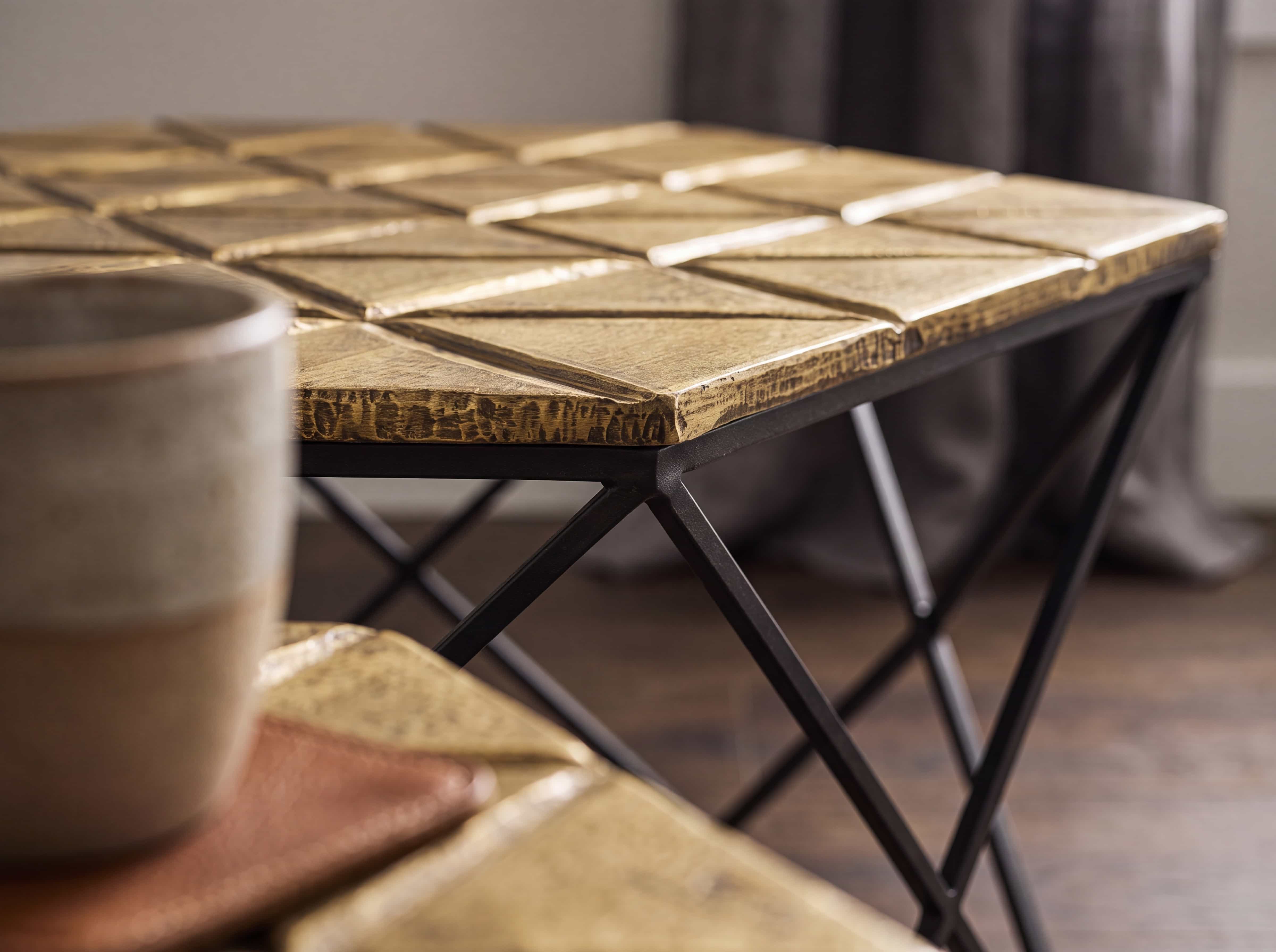 Couchtisch mit quadratischer, goldfarbener Metallplatte und schwarzem Kreuzgestell aus Metall
