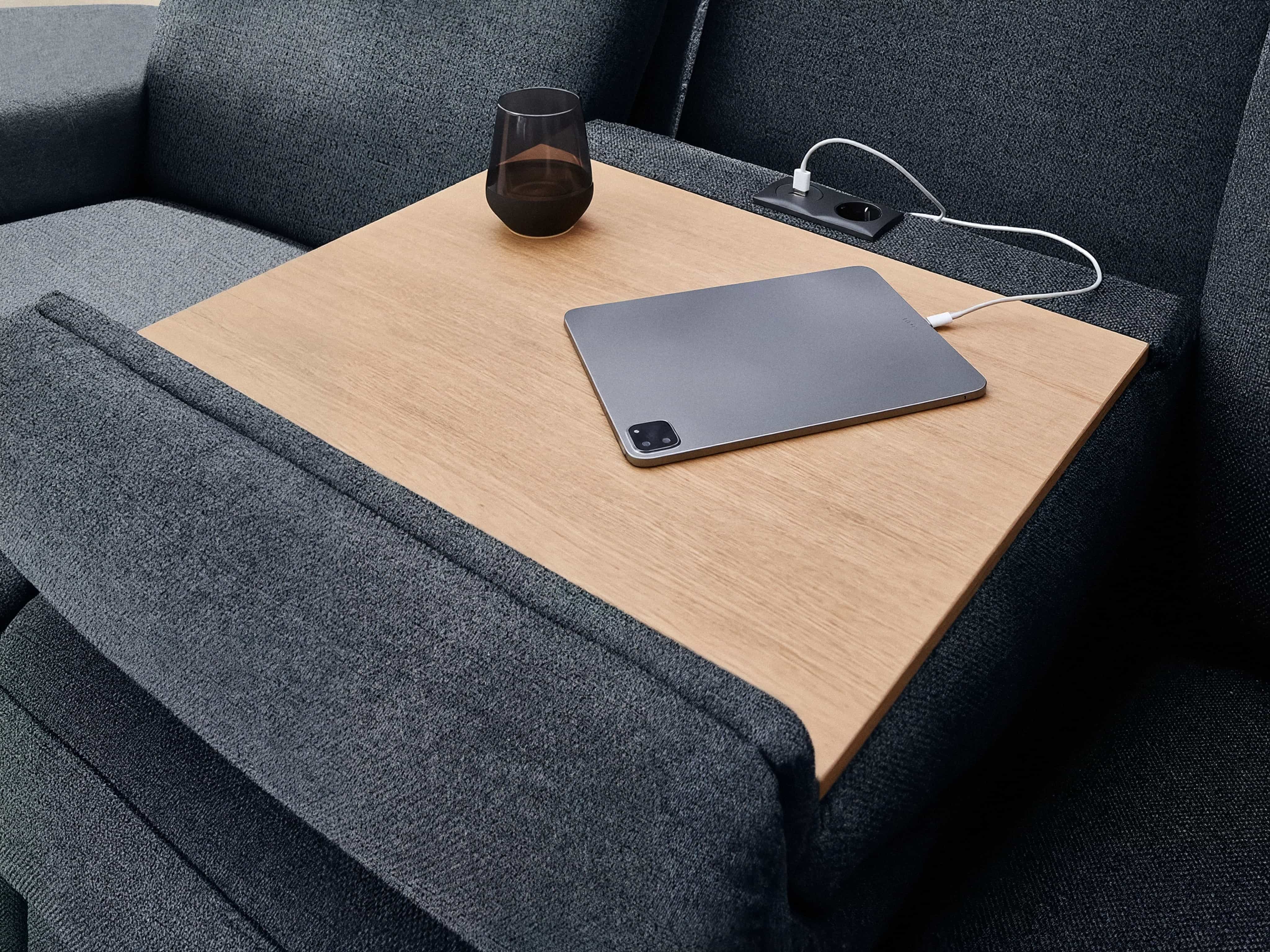 Ecksofa mit grauem Stoffbezug, integrierter Holzablage und USB-Anschluss in der Armlehne