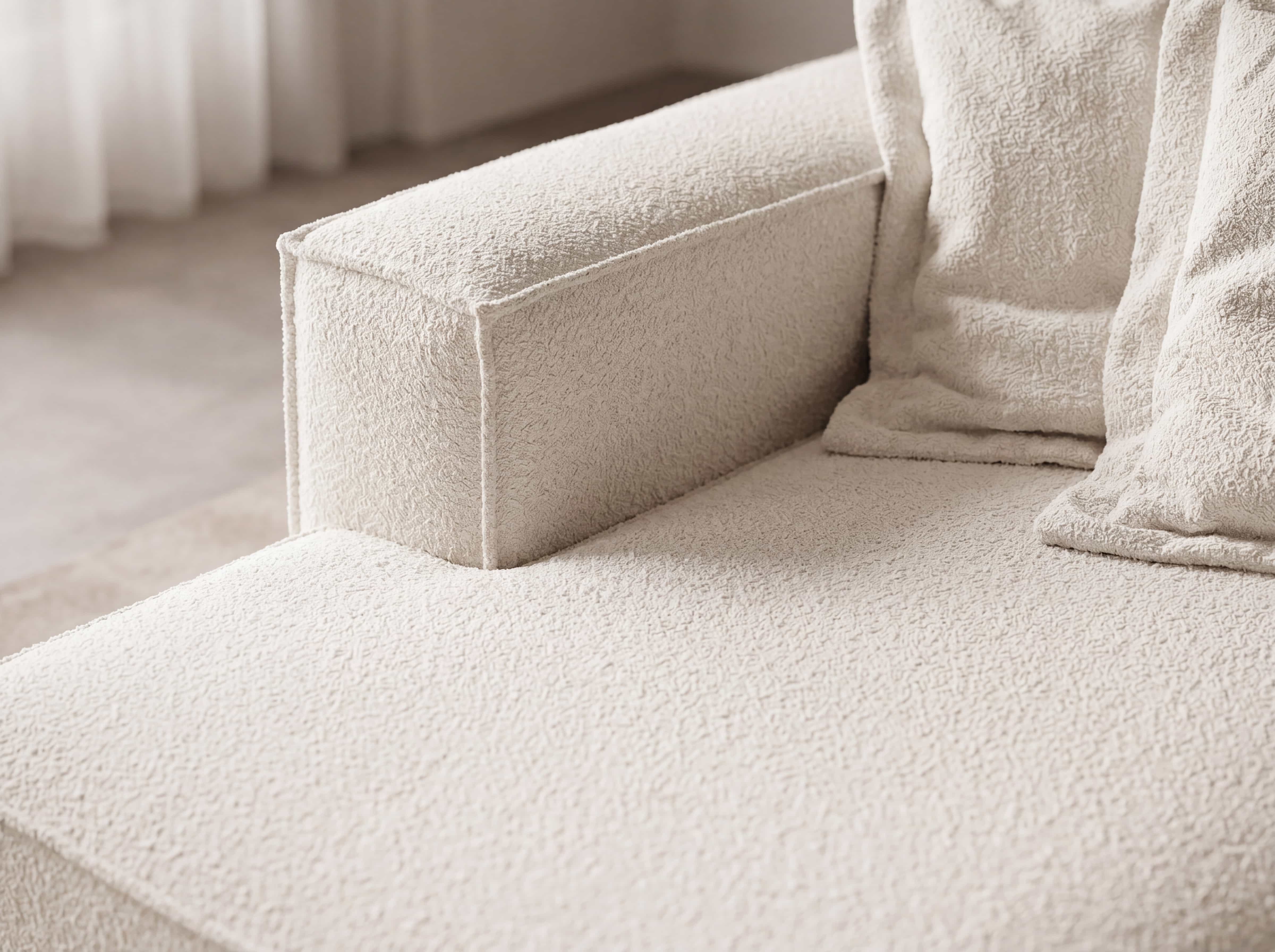 Ecksofa Cosy mit beigem Bouclé-Stoffbezug, breiter Armlehne und eckigen Rückenkissen