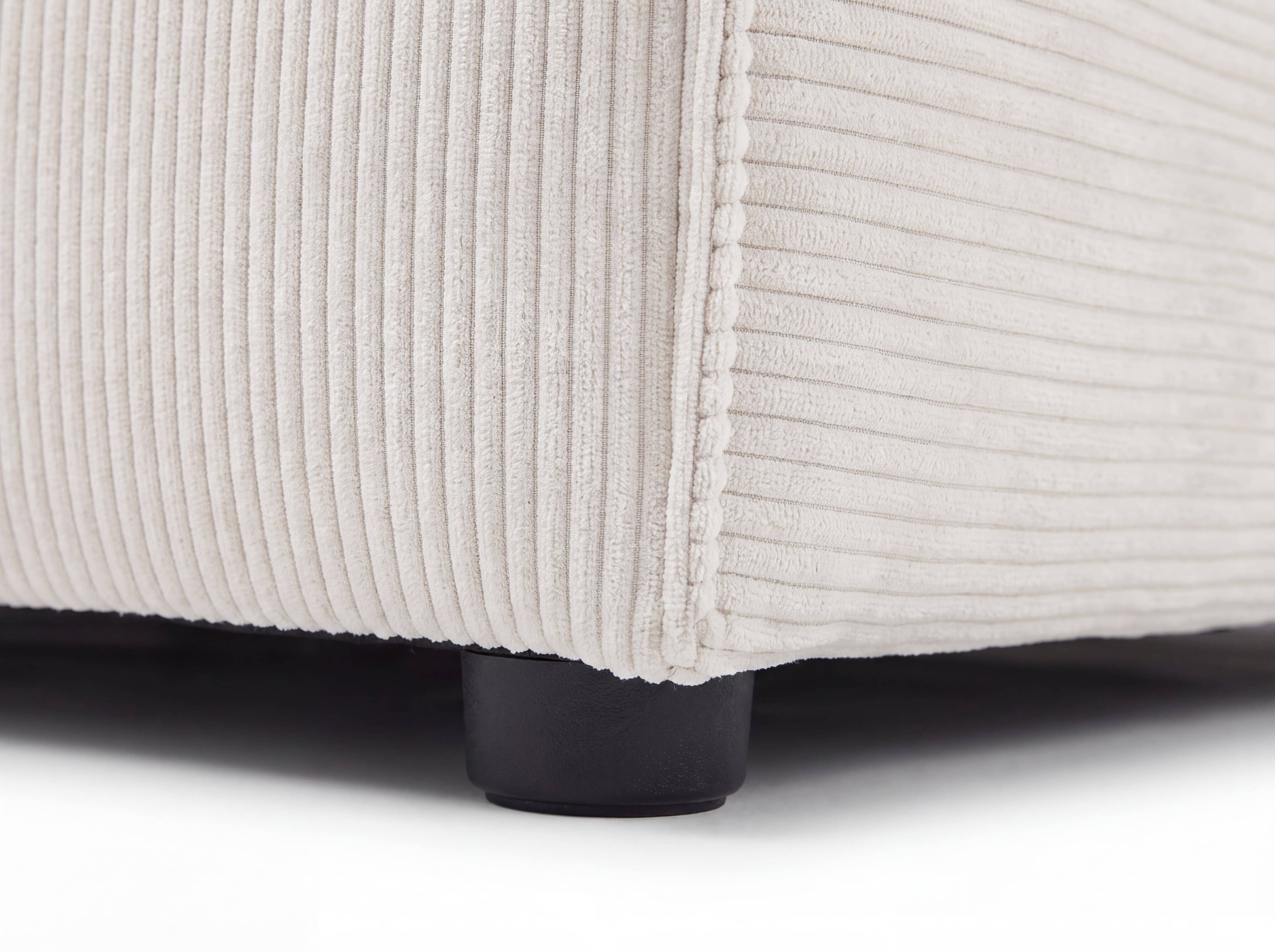 Nahaufnahme eines Sofafußes mit beigem Cordbezug und sichtbarer Steppnaht an der unteren Sofaecke.