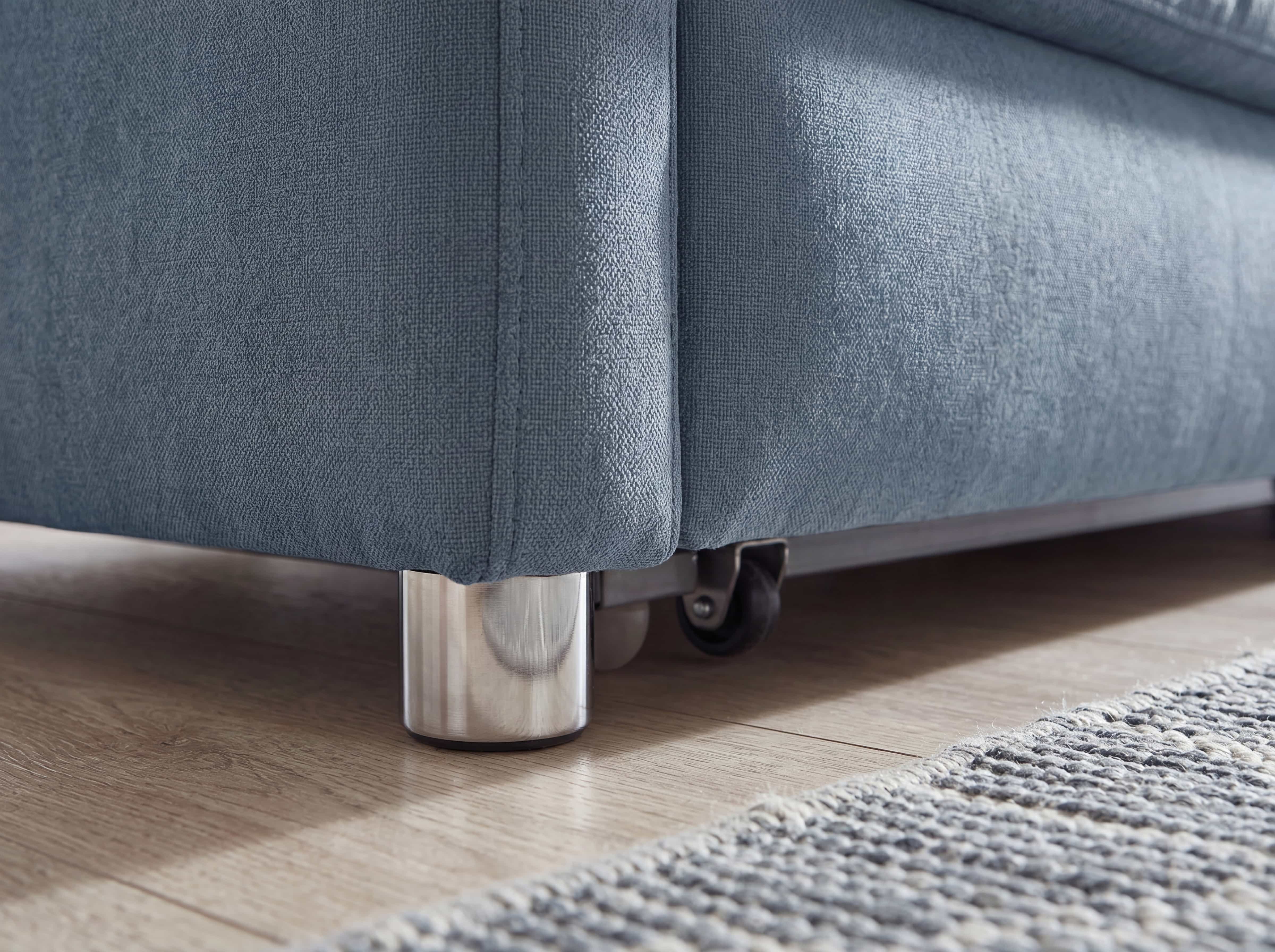 Sofa-Ecke mit blauem Stoffbezug und rundem Metallfuß, sichtbarem Rollenmechanismus am Gestell