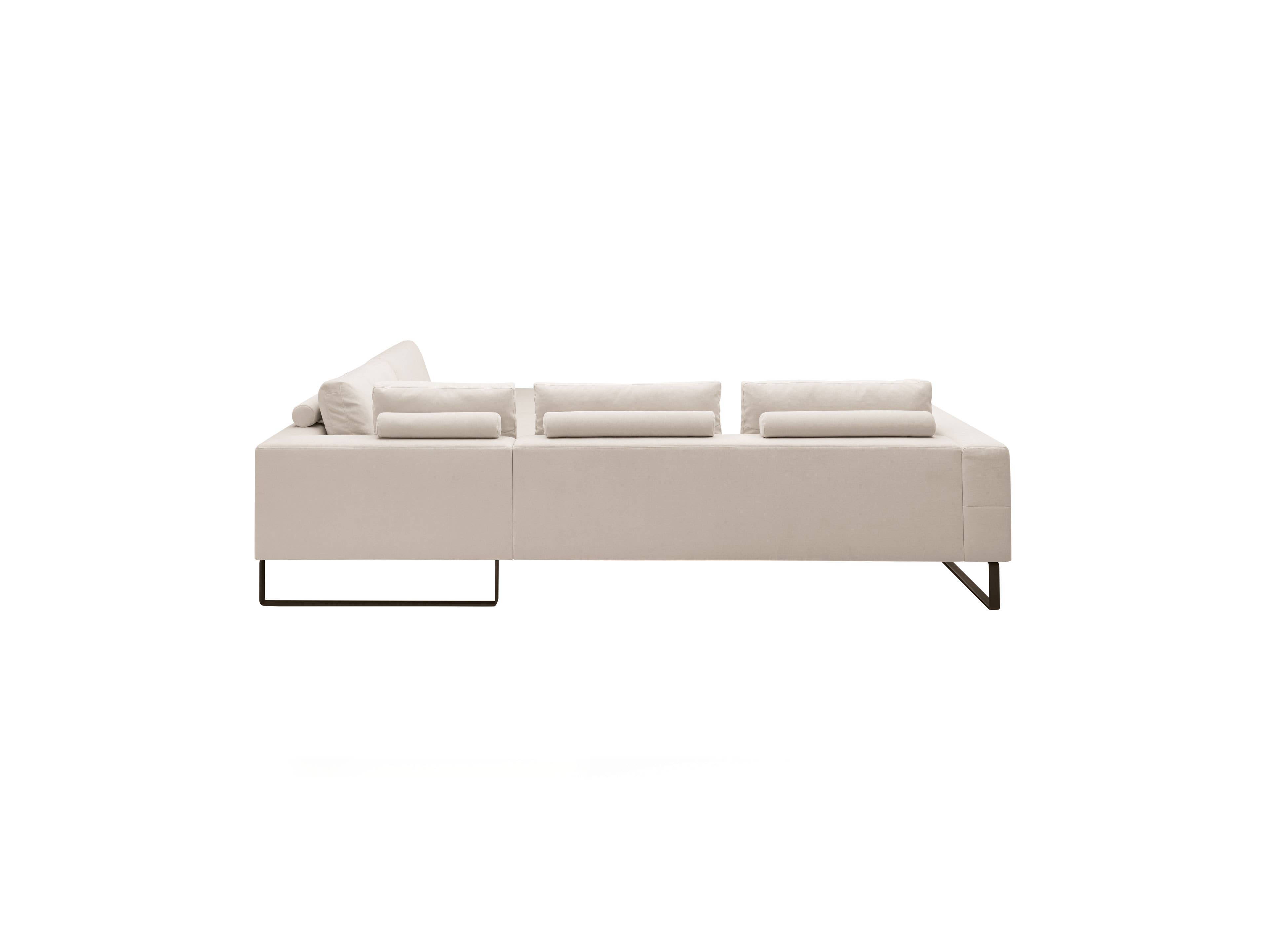 Ecksofa Modell in hellem Stoff mit niedrigen Rückenkissen und filigranen Metallfüßen seitlich
