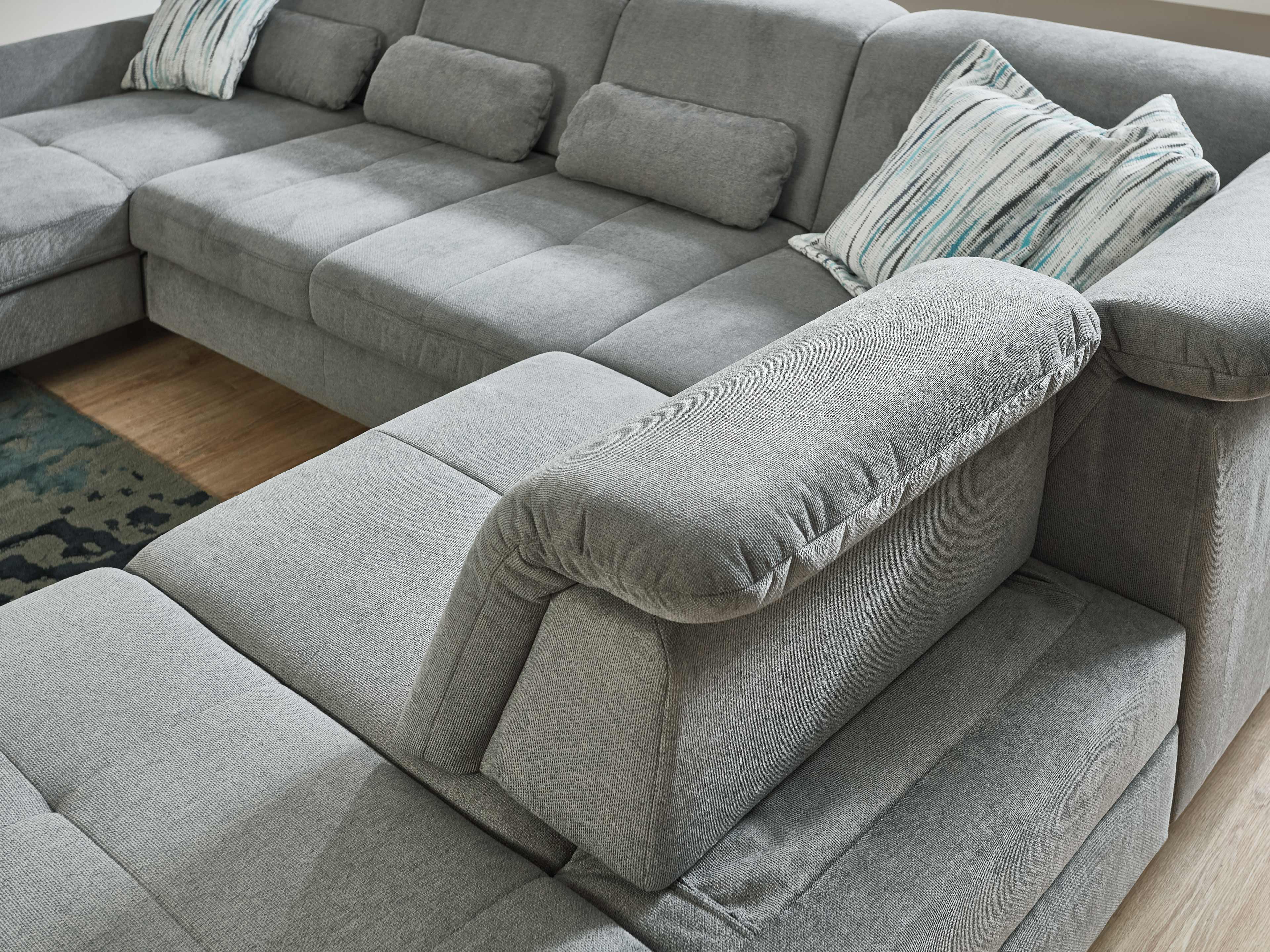 Ecksofa Kabs Polsterwelt mit grauem Stoffbezug, gepolsterten Armlehnen und losen Rückenkissen