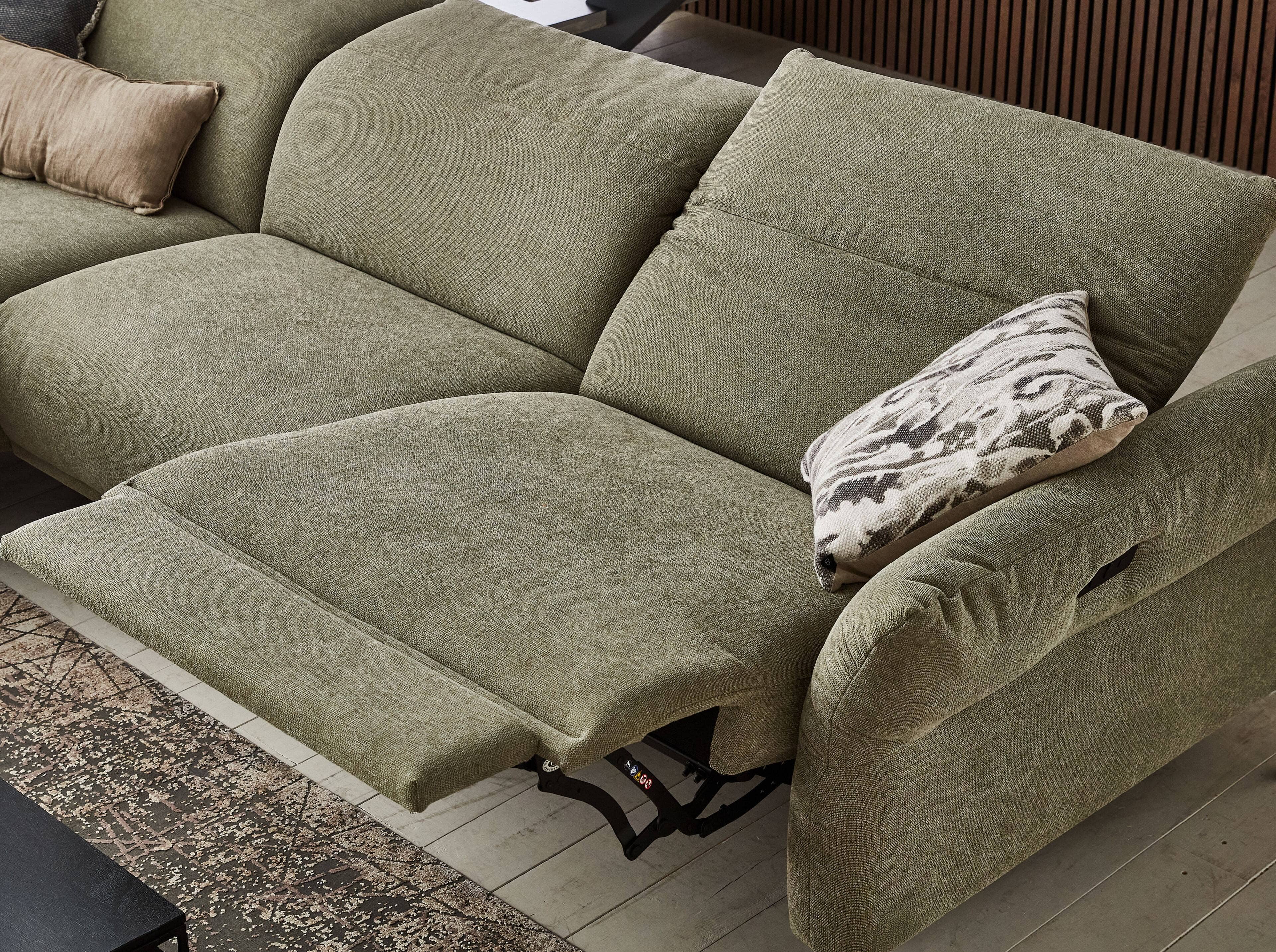 Ecksofa mit grünem Stoffbezug, rechtsseitiger Relaxfunktion und gepolsterter Armlehne