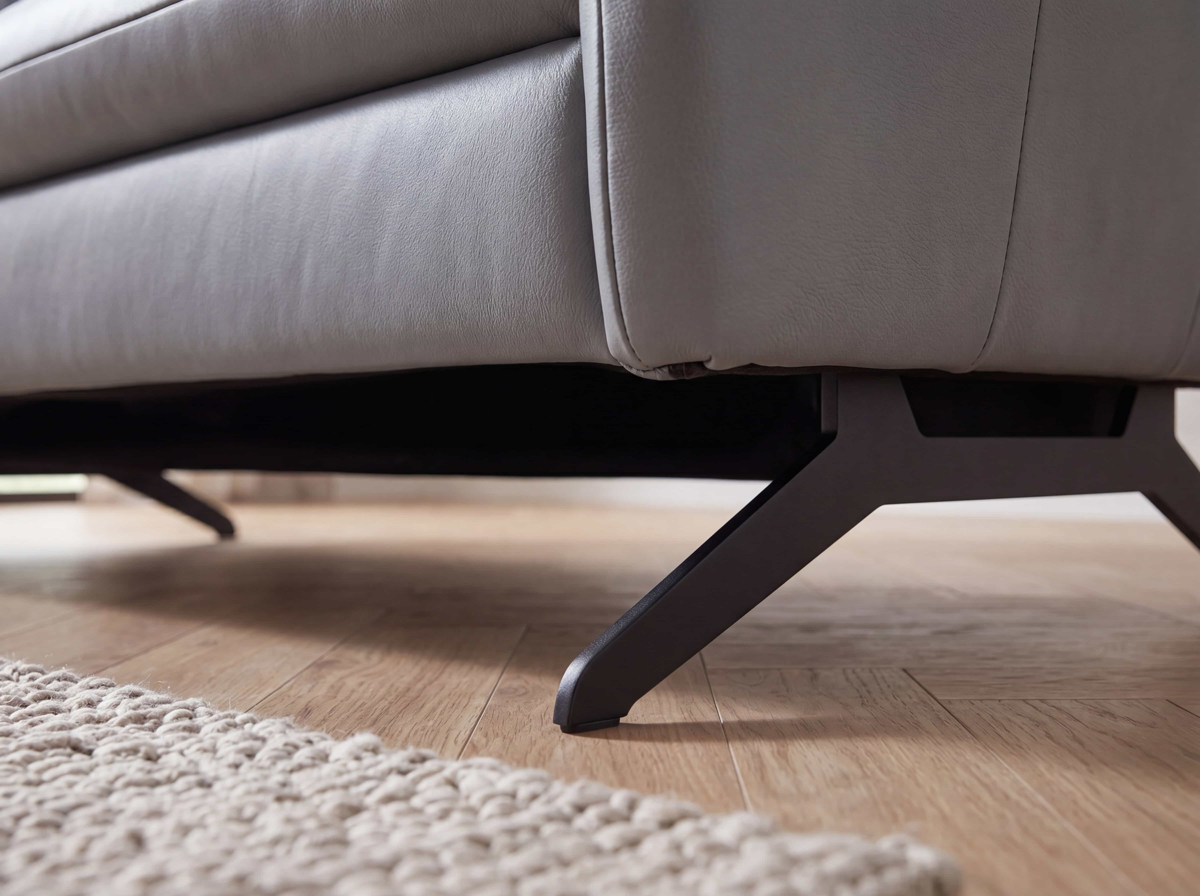Ledersofa mit grauem Bezug und schwarzen Metallfüßen, Detailaufnahme des Gestells auf Holzboden