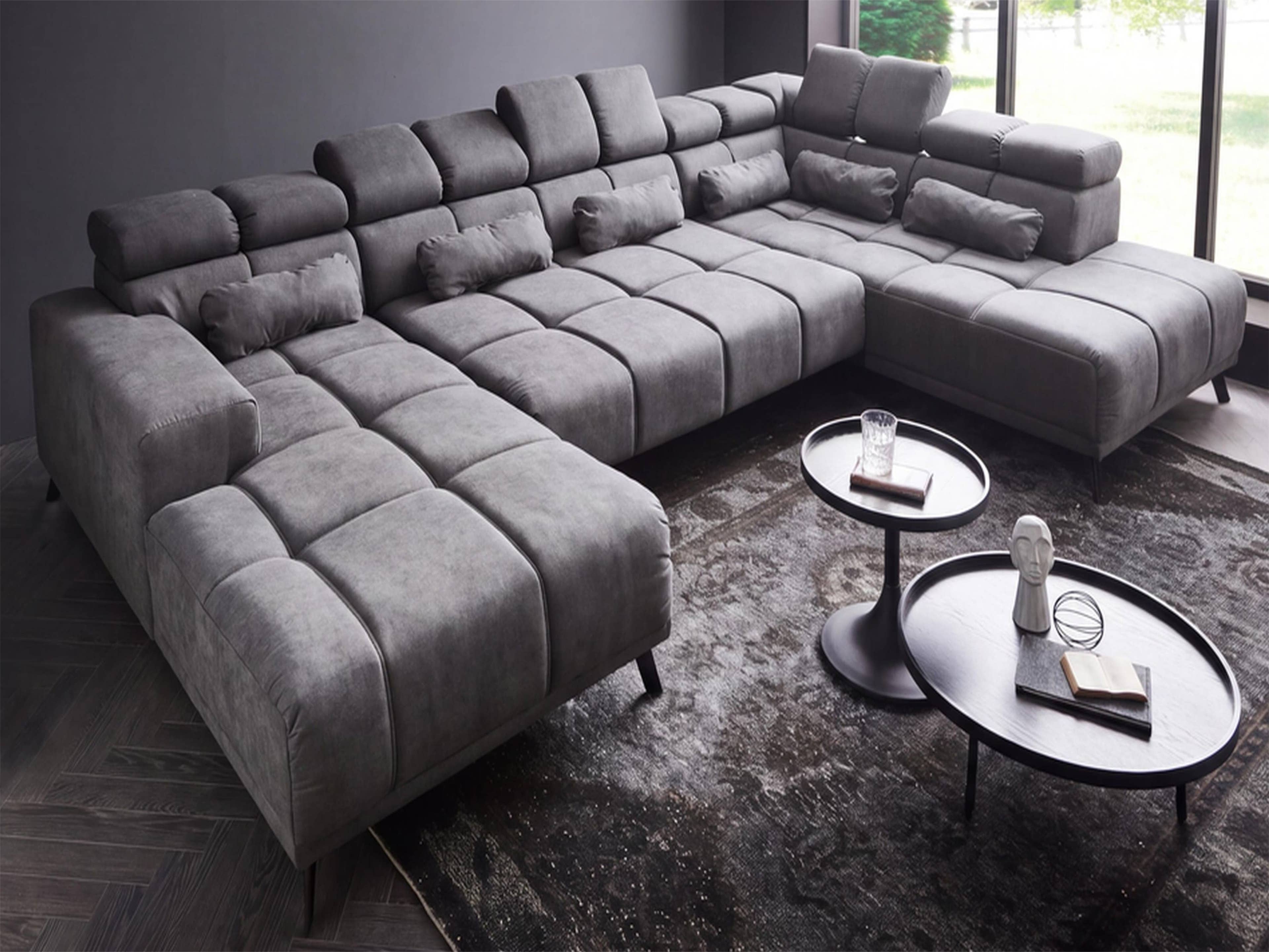 Ecksofa Kabs Polsterwelt mit grauem Stoffbezug, breiten Armlehnen, verstellbaren Kopfstützen und Steppung