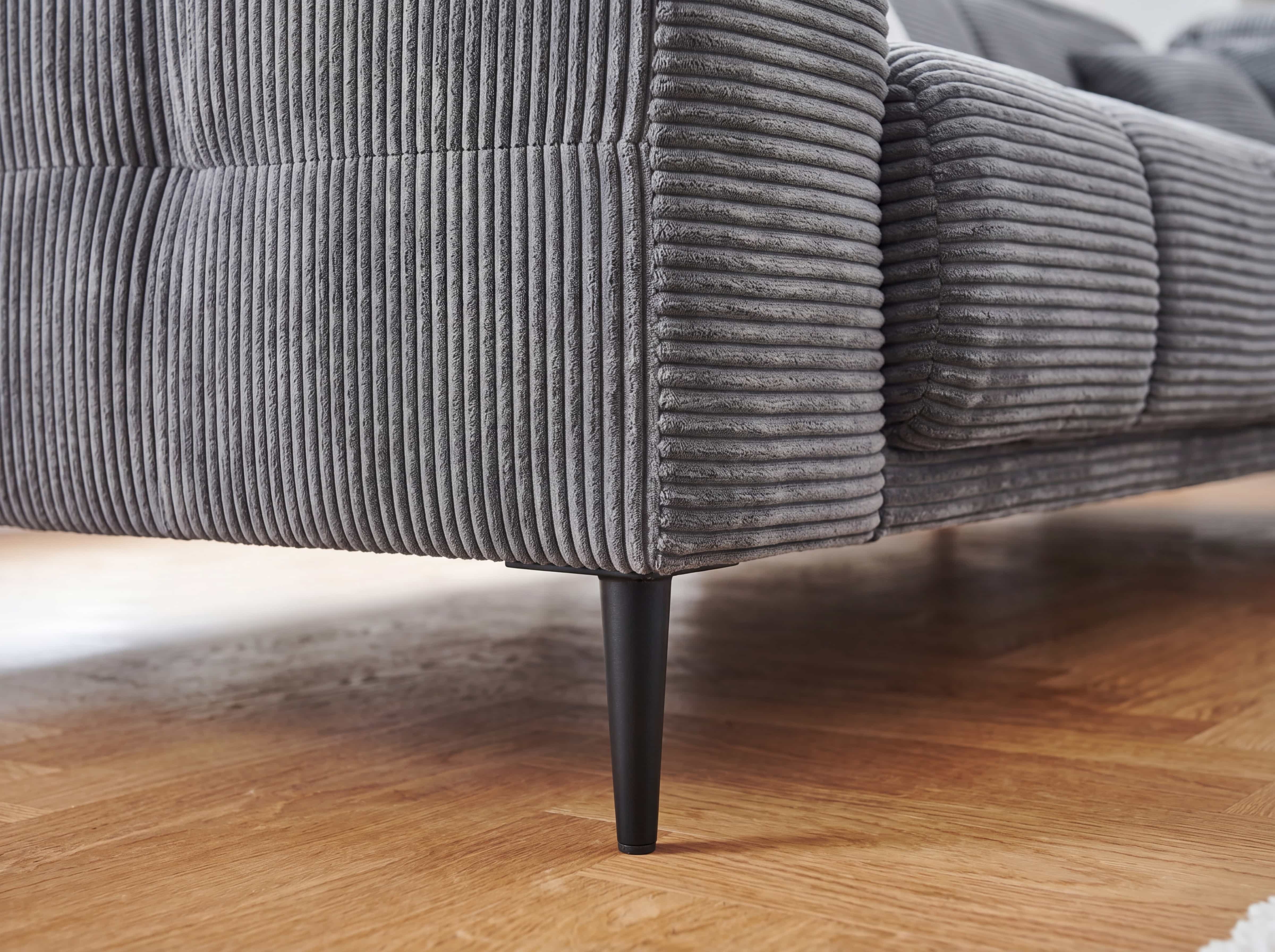 Ecksofa Irun – Detailansicht des grauen Cordbezugs mit senkrechter Struktur und schwarzen Füßen
