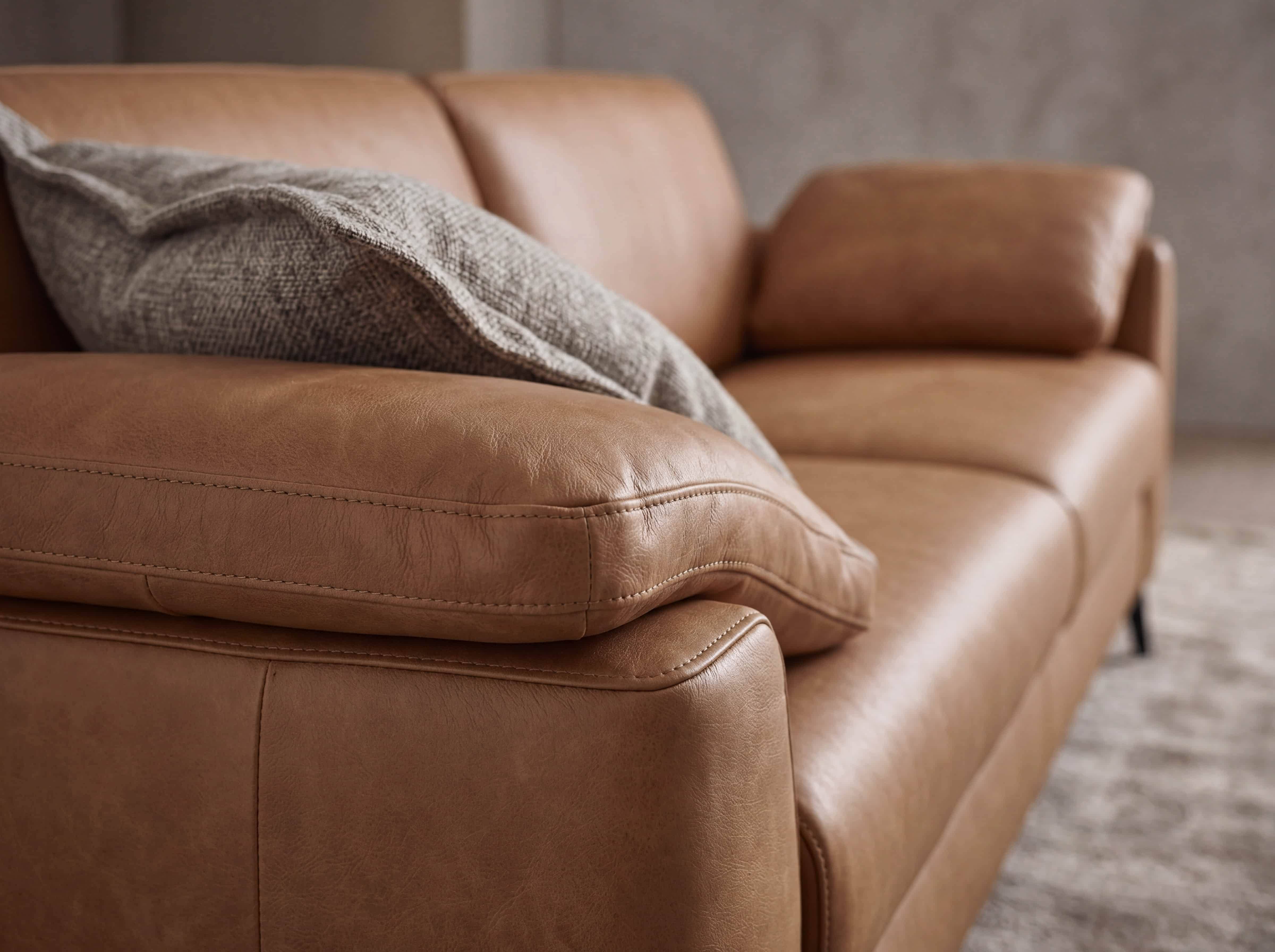 Ecksofa Kabs Polsterwelt aus cognacfarbenem Leder mit breiten Armlehnen und strukturiertem Kissen
