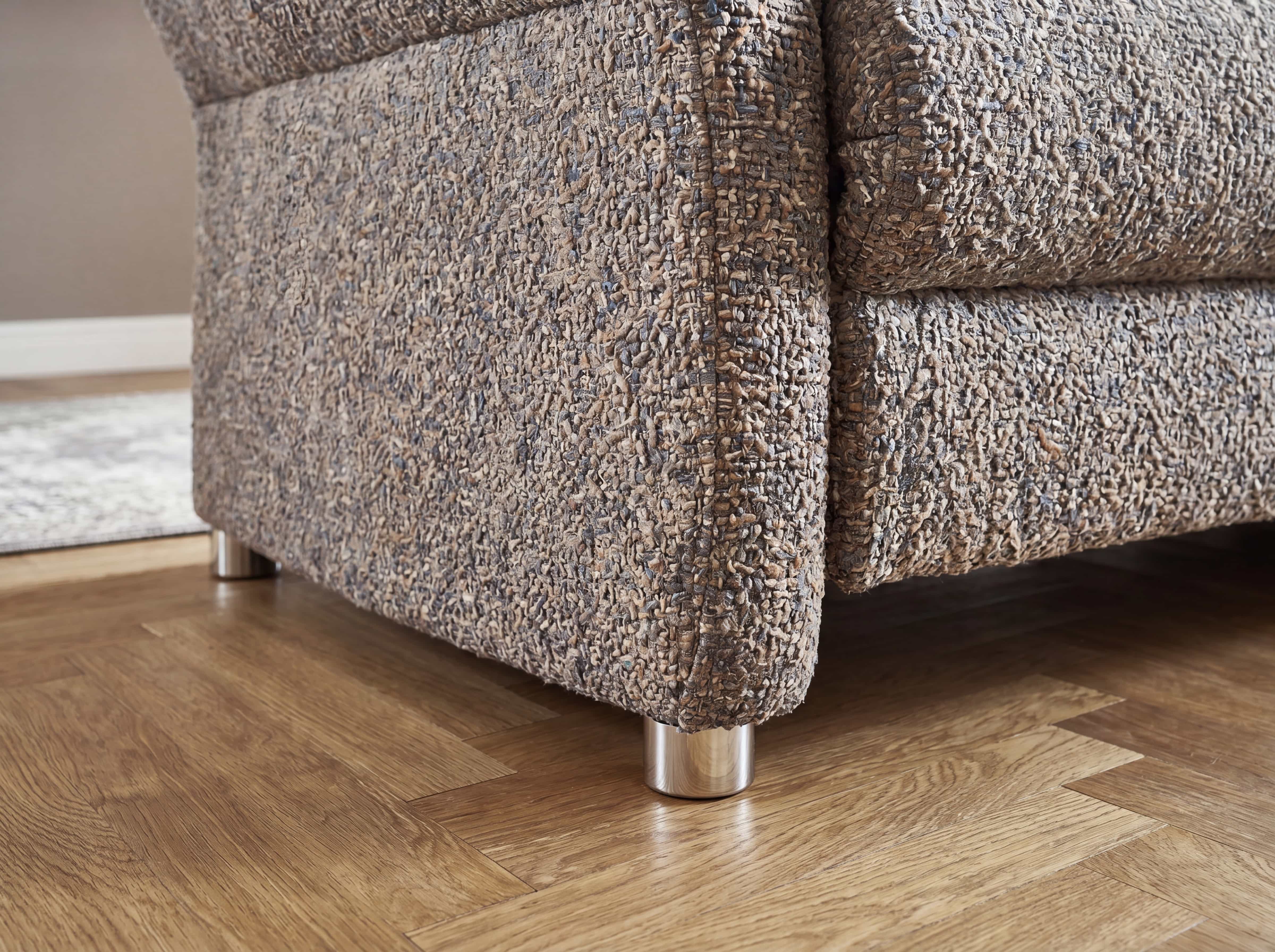 Einzelsofa Pirona – Detailansicht des braunen Strukturbezugs mit runden Metallfüßen