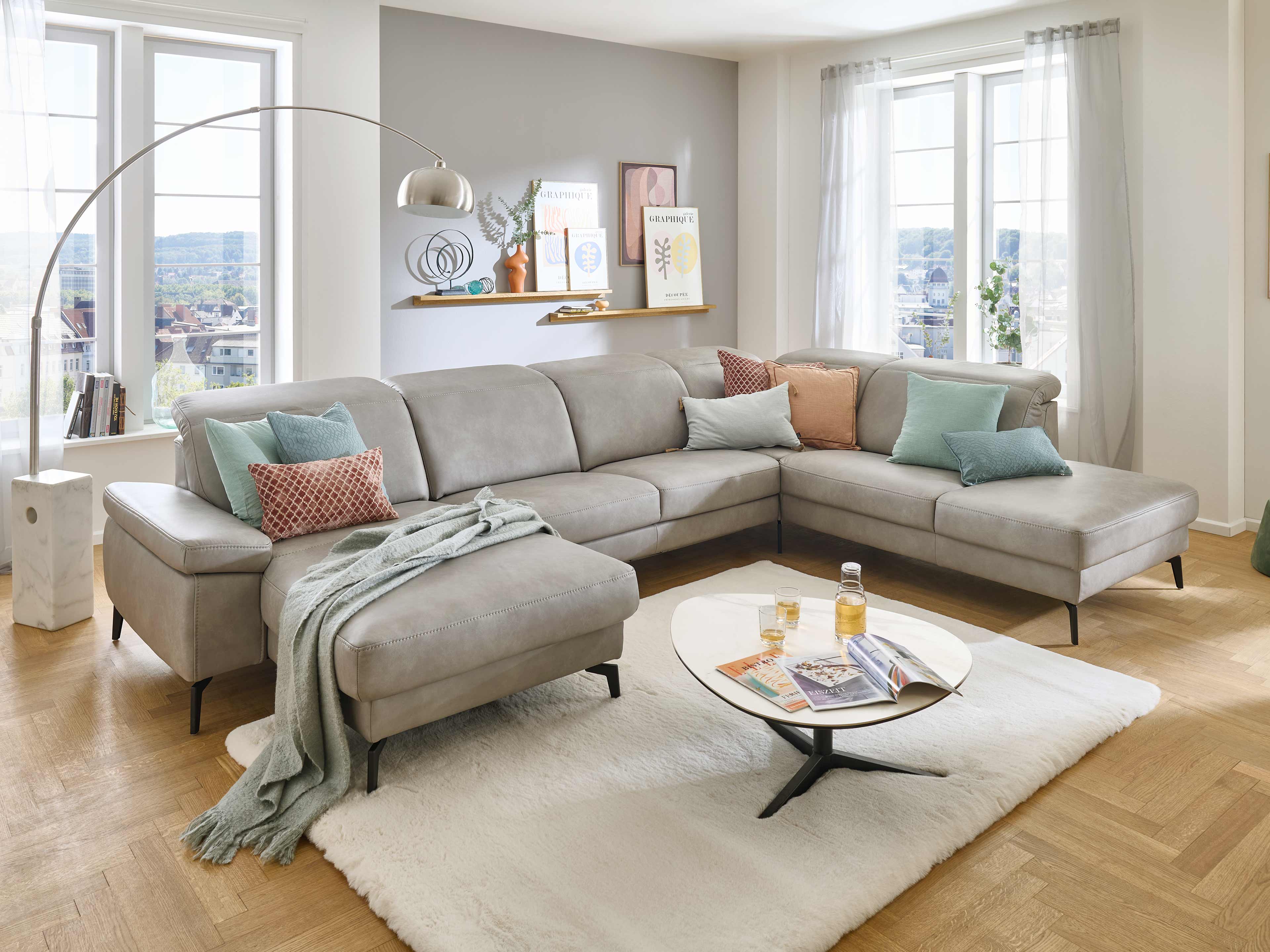 Ecksofa mit hellgrauem Lederbezug, L-Form, gepolsterte Rückenlehnen und schwarze Metallfüße