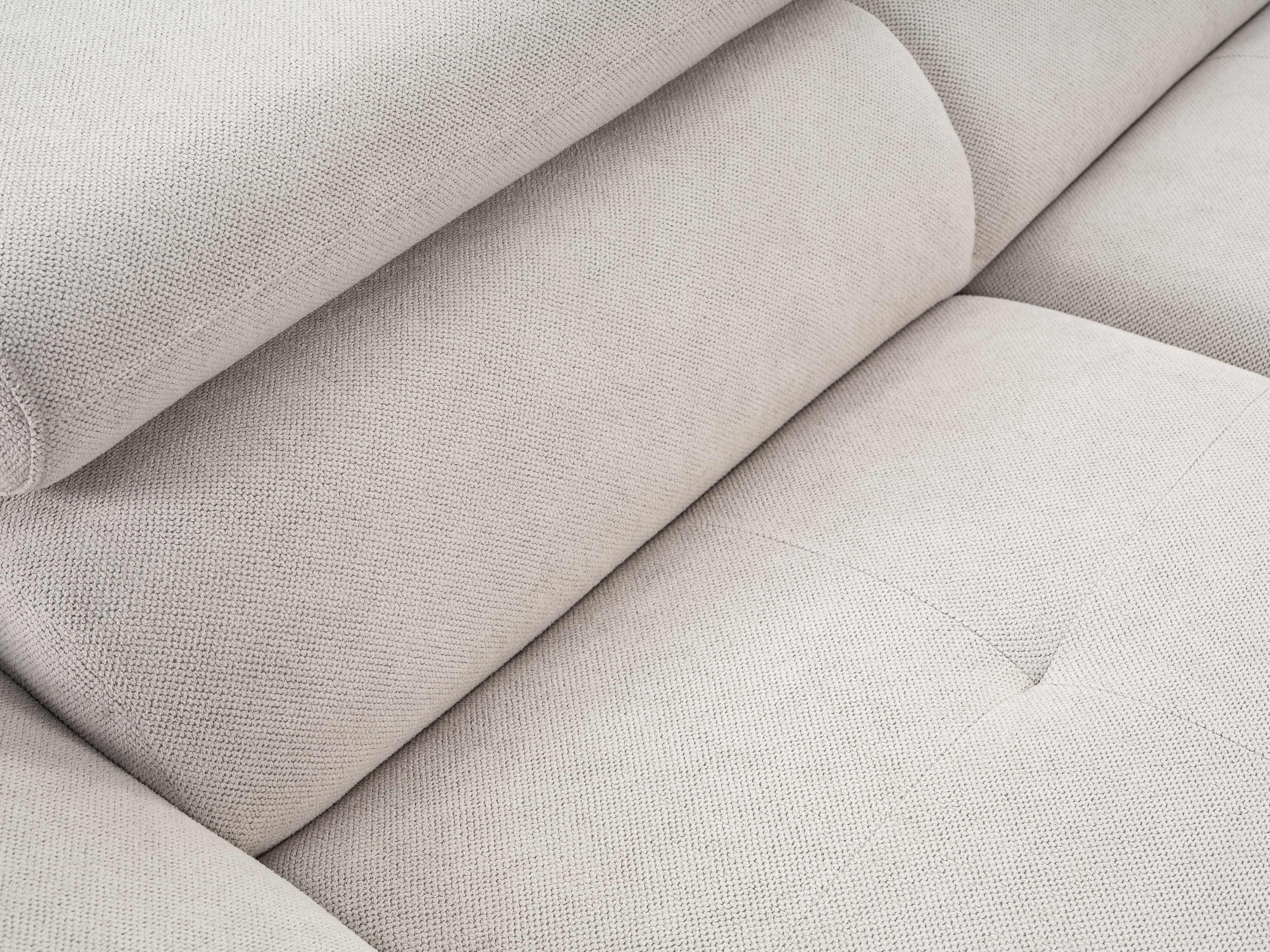 Sofadetail mit hellgrauem Stoffbezug und sichtbarer Polsterung, strukturierte Oberfläche