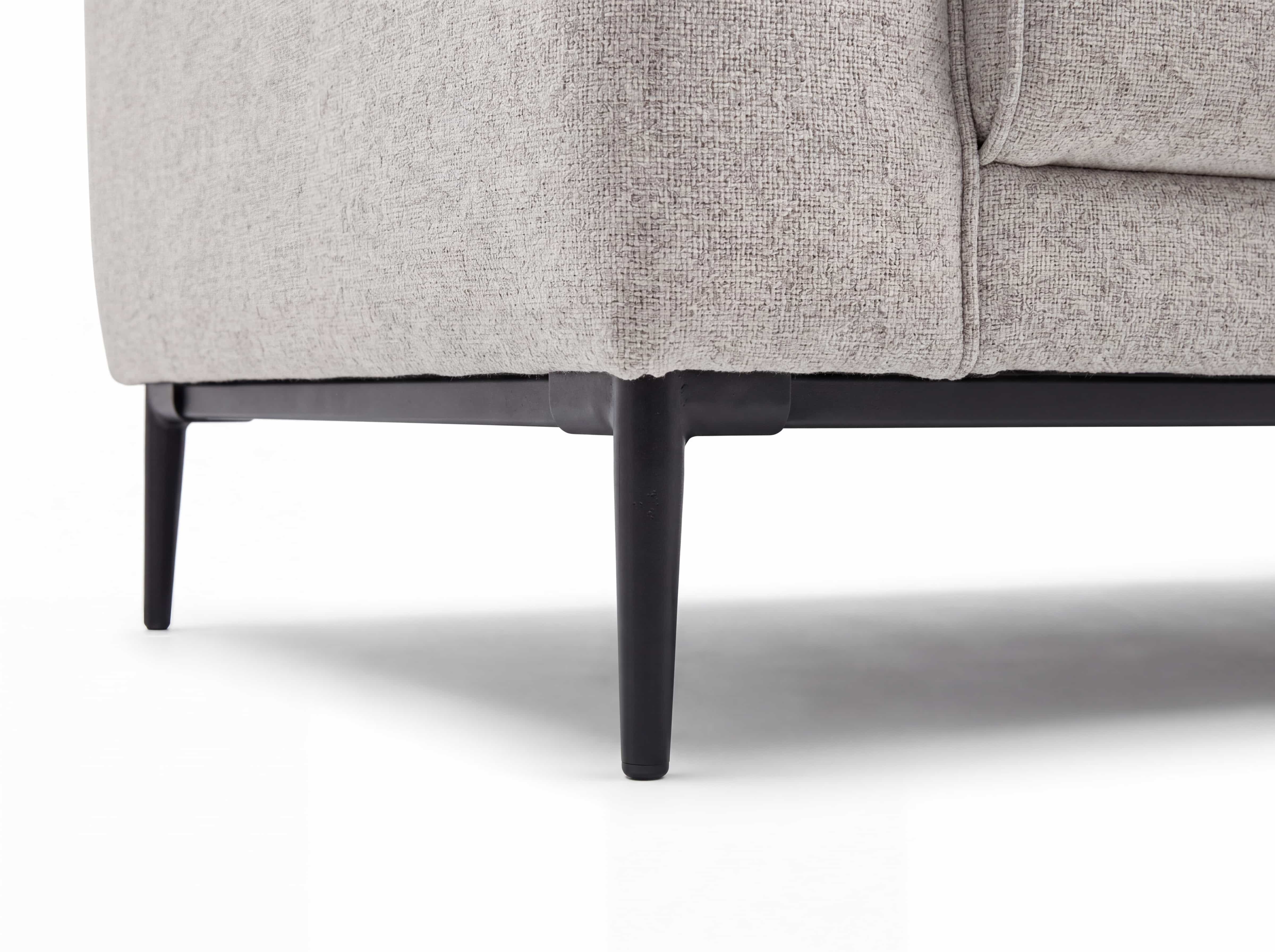 Sofa mit hellem Stoffbezug und schwarzen, schmalen Metallfüßen in moderner Linienführung