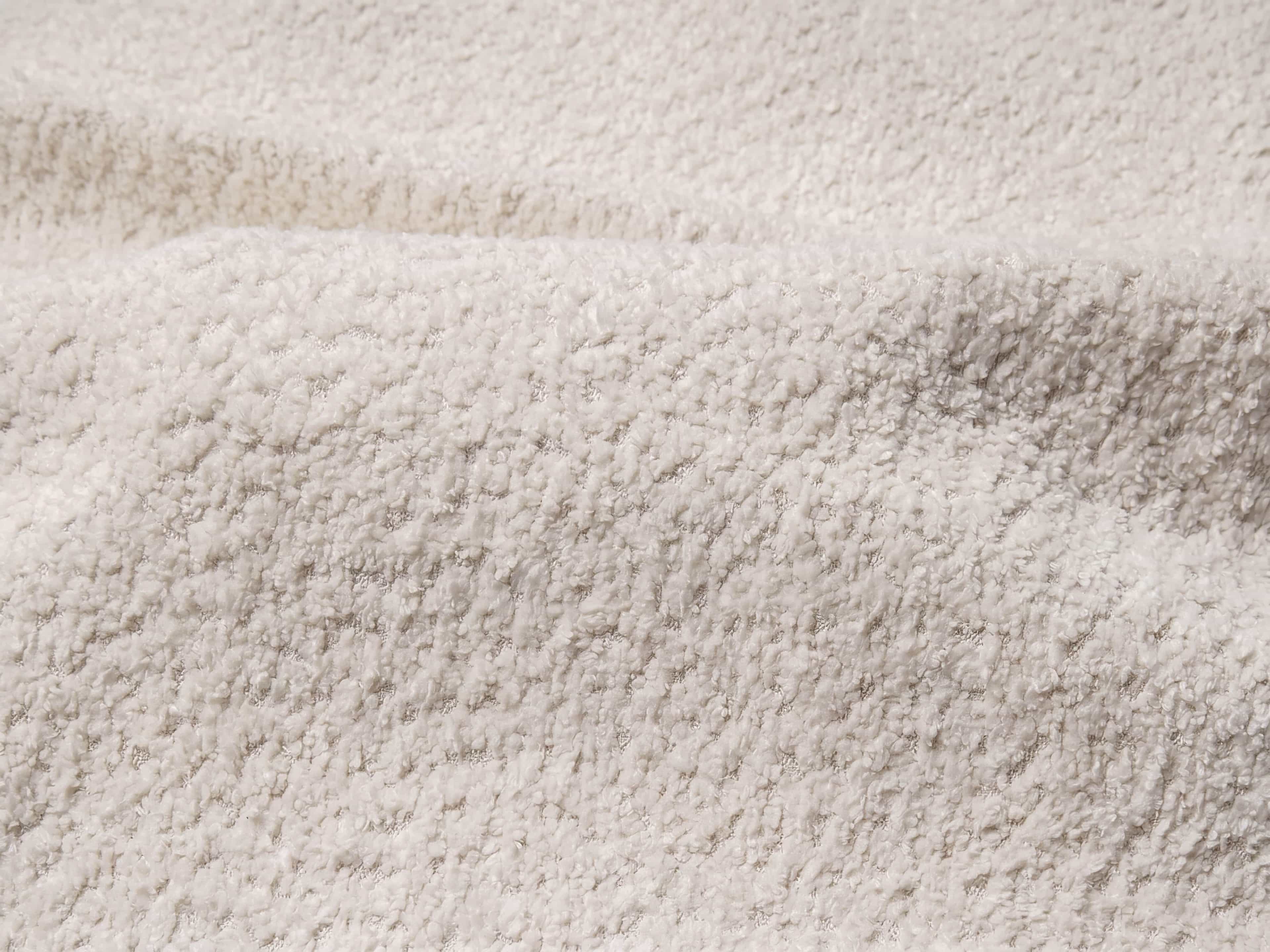 Strukturierter Bouclé-Stoff in Creme mit gleichmäßiger, weicher und leicht erhobener Oberflächenstruktur