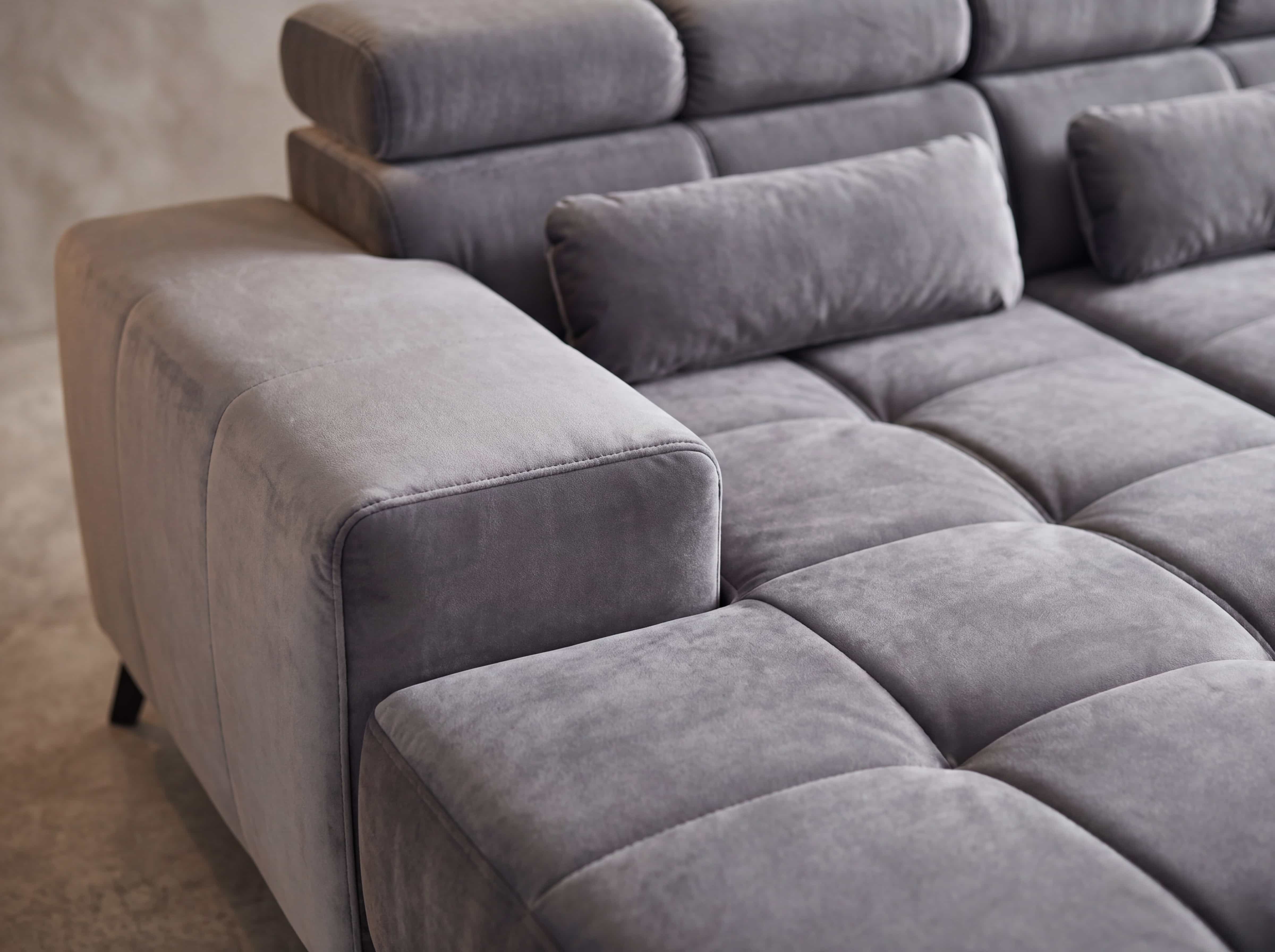 Ecksofa Kabs mit grauem Stoffbezug, breiten Armlehnen und gepolsterten Rückenlehnen