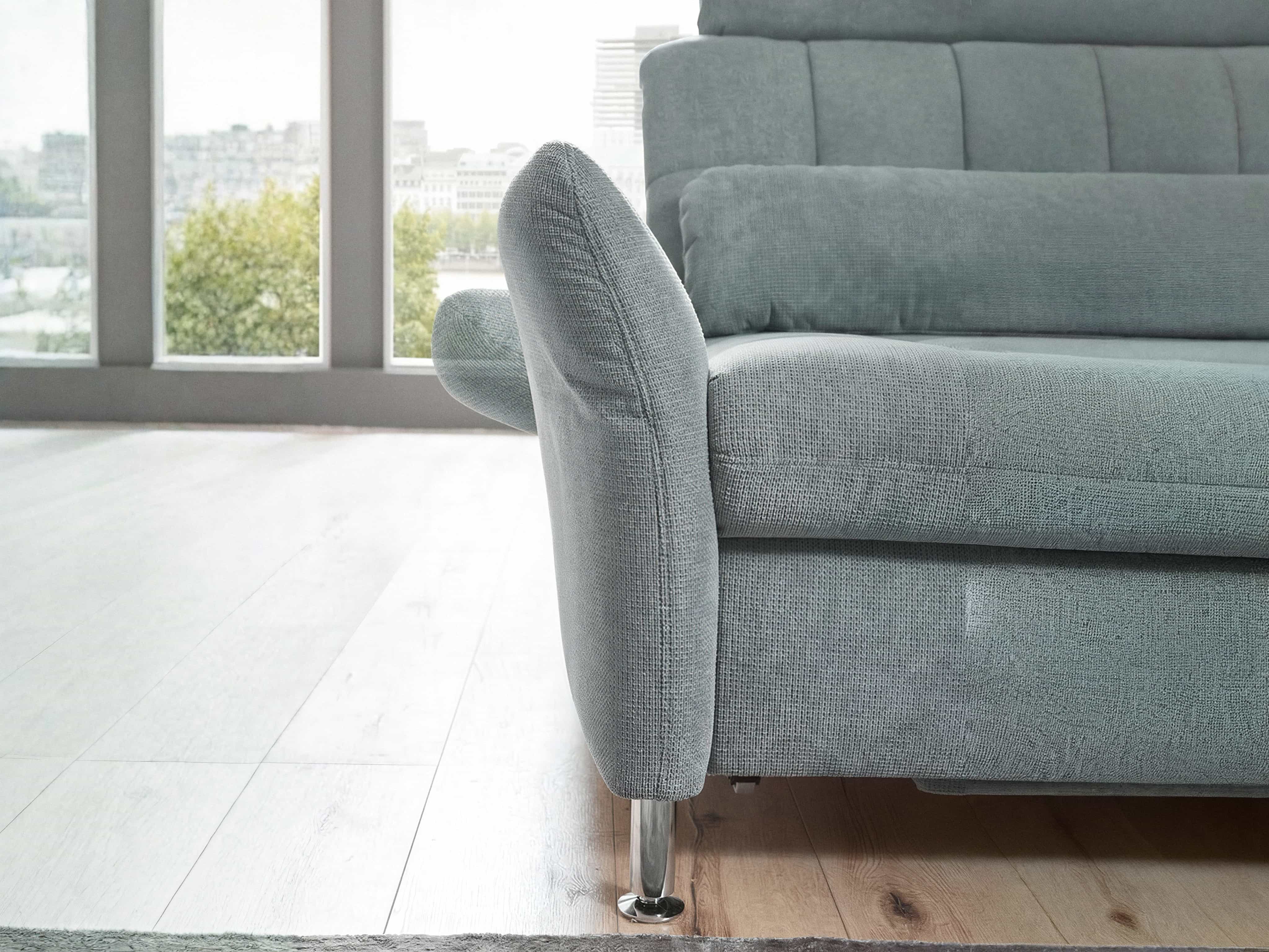 Ecksofa mit hellgrauem Stoffbezug, abgerundeter Armlehne und verchromtem Metallfuß