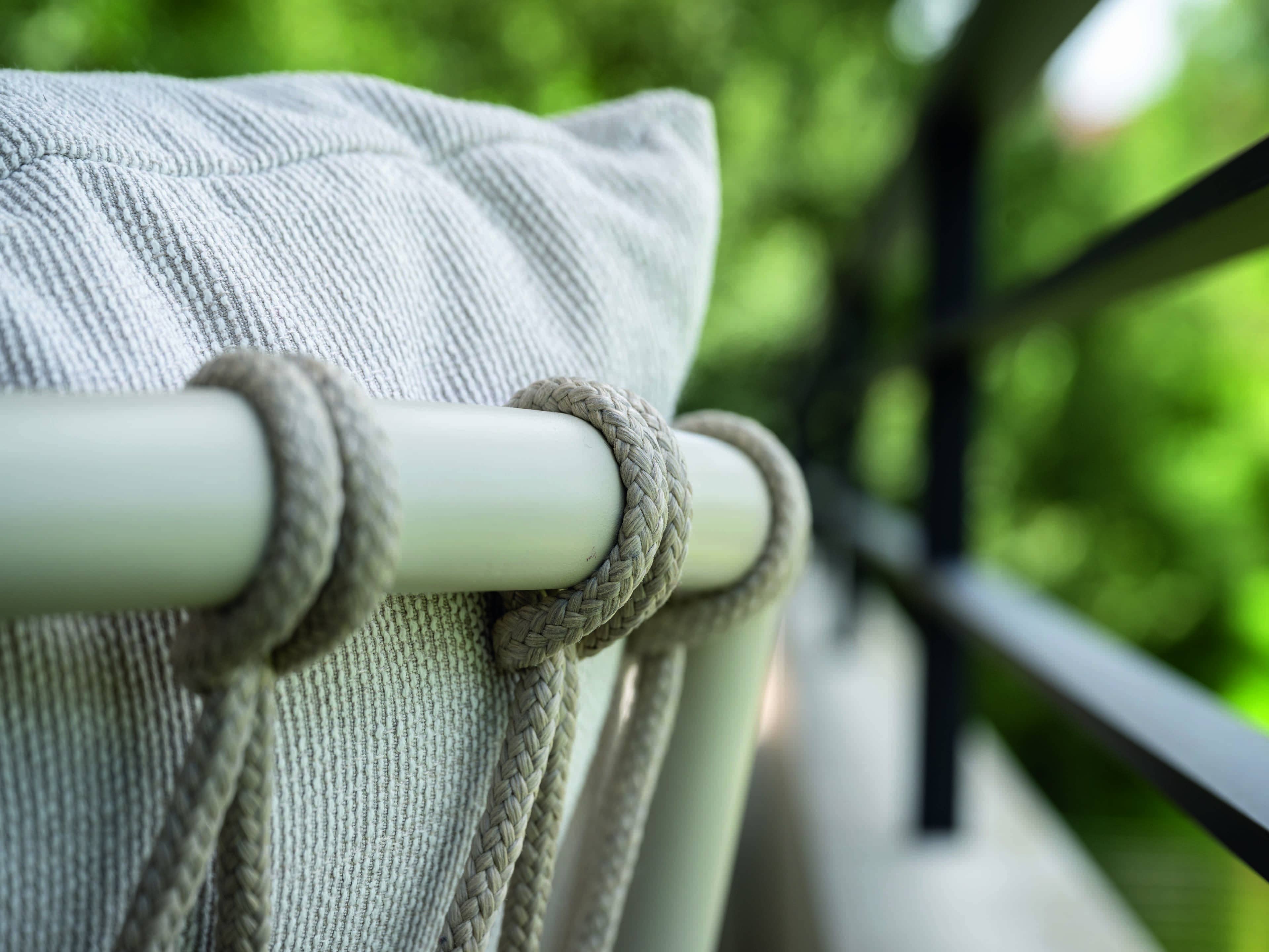 Beiger Outdoorstuhl mit textilem Kissen und geflochtenen Kordeln an heller Rückenlehne aus Metall