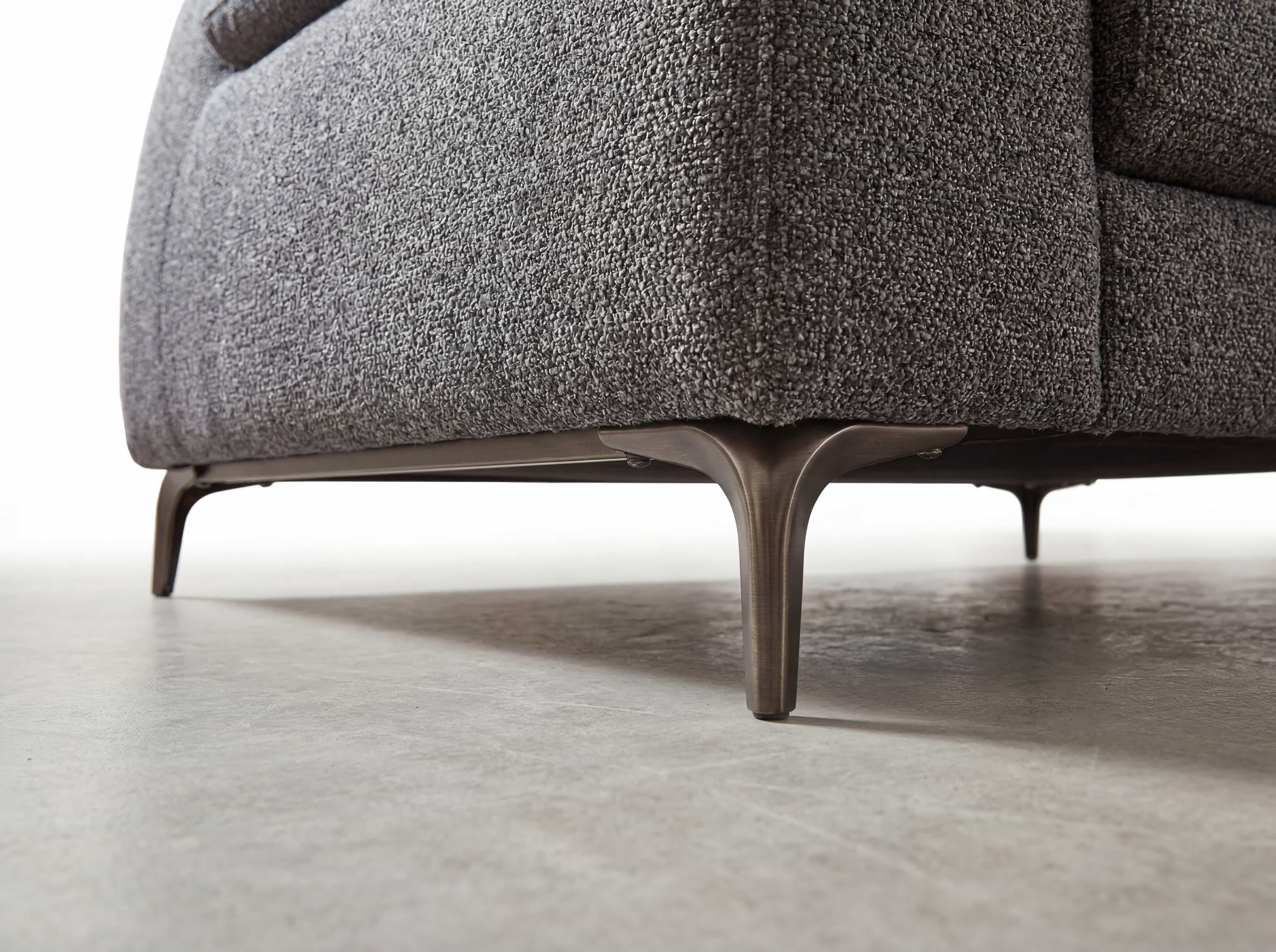 Ecksofa mit grauem Stoffbezug und abgerundeter Ecke, Metallfüße in gebürsteter Optik, Nahaufnahme