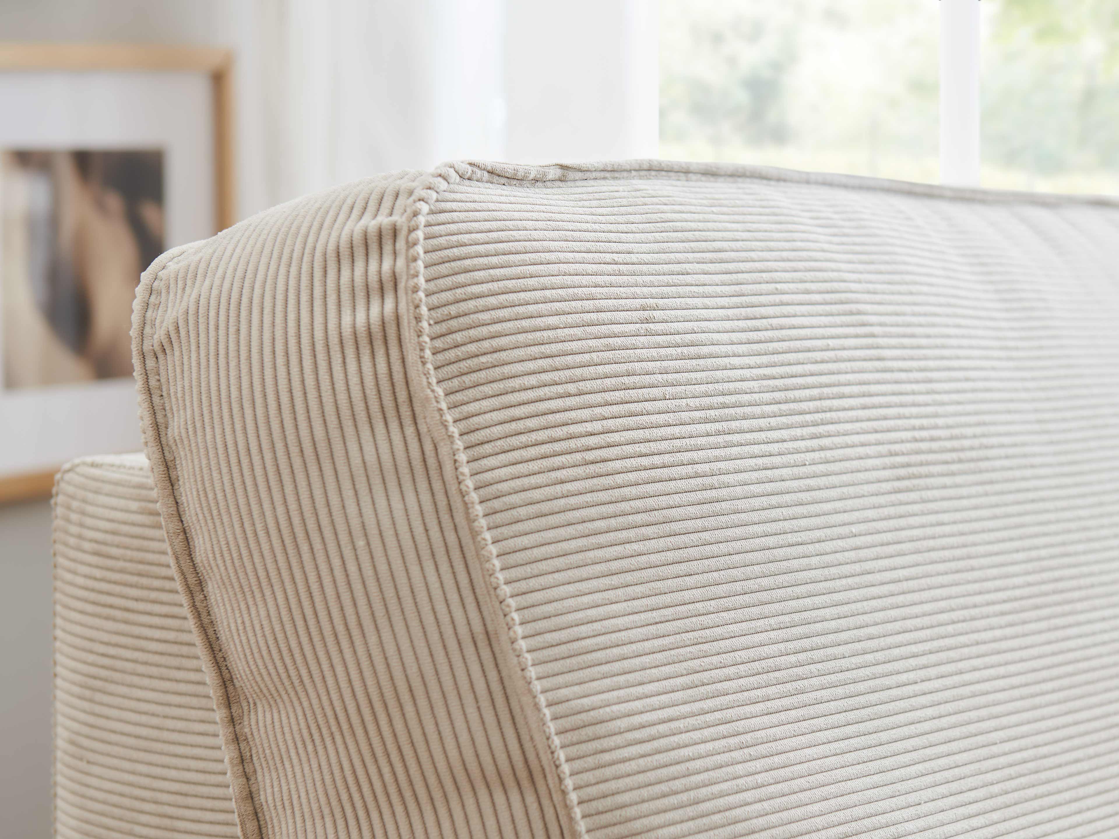 Rückenlehne eines Sofas mit beigem, fein geripptem Cordbezug und sichtbarer Kantennaht