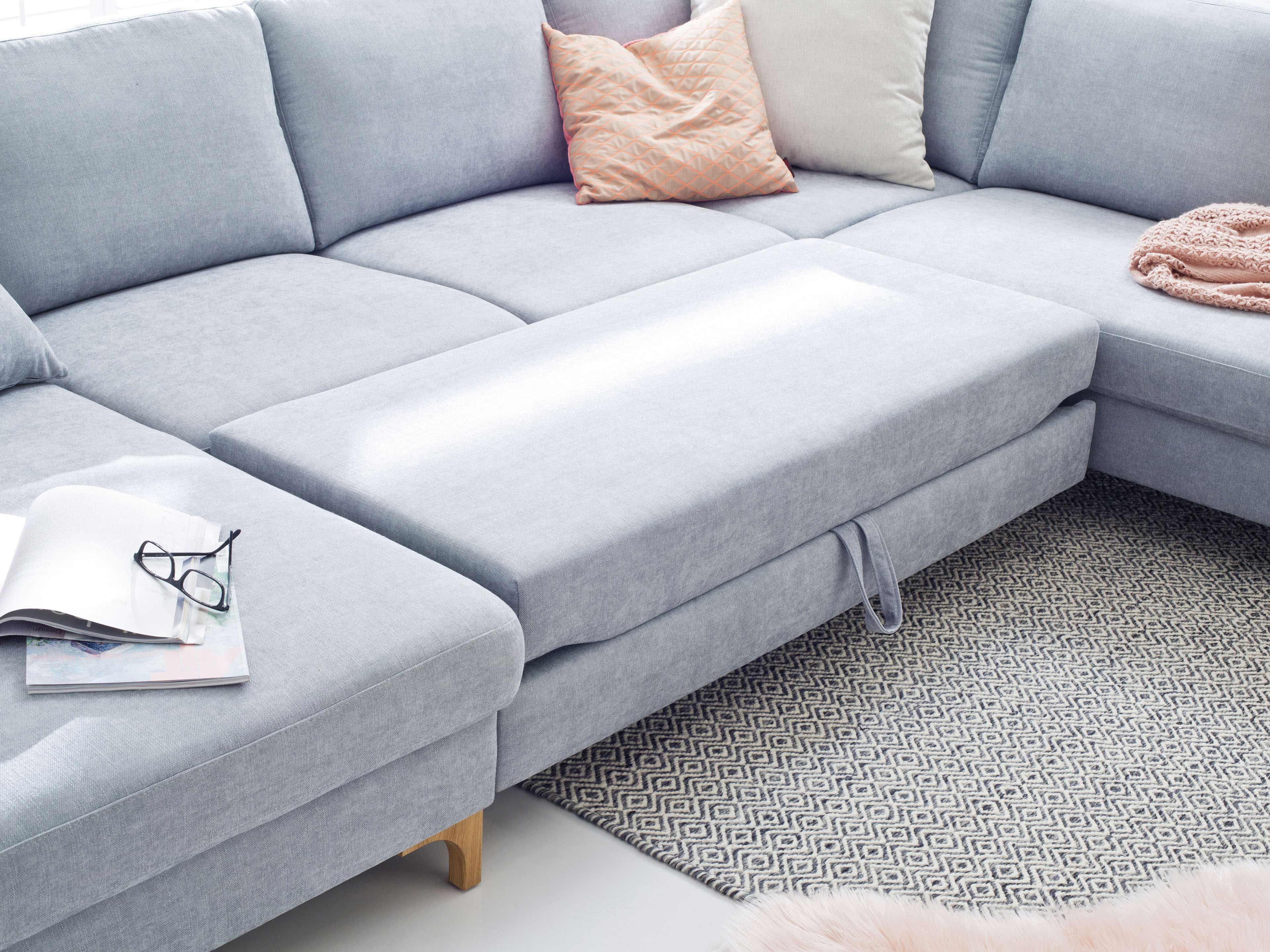 Ecksofa mit hellgrauem Stoffbezug, rechteckiger Liegefläche und sichtbaren Holzbodenfüßen
