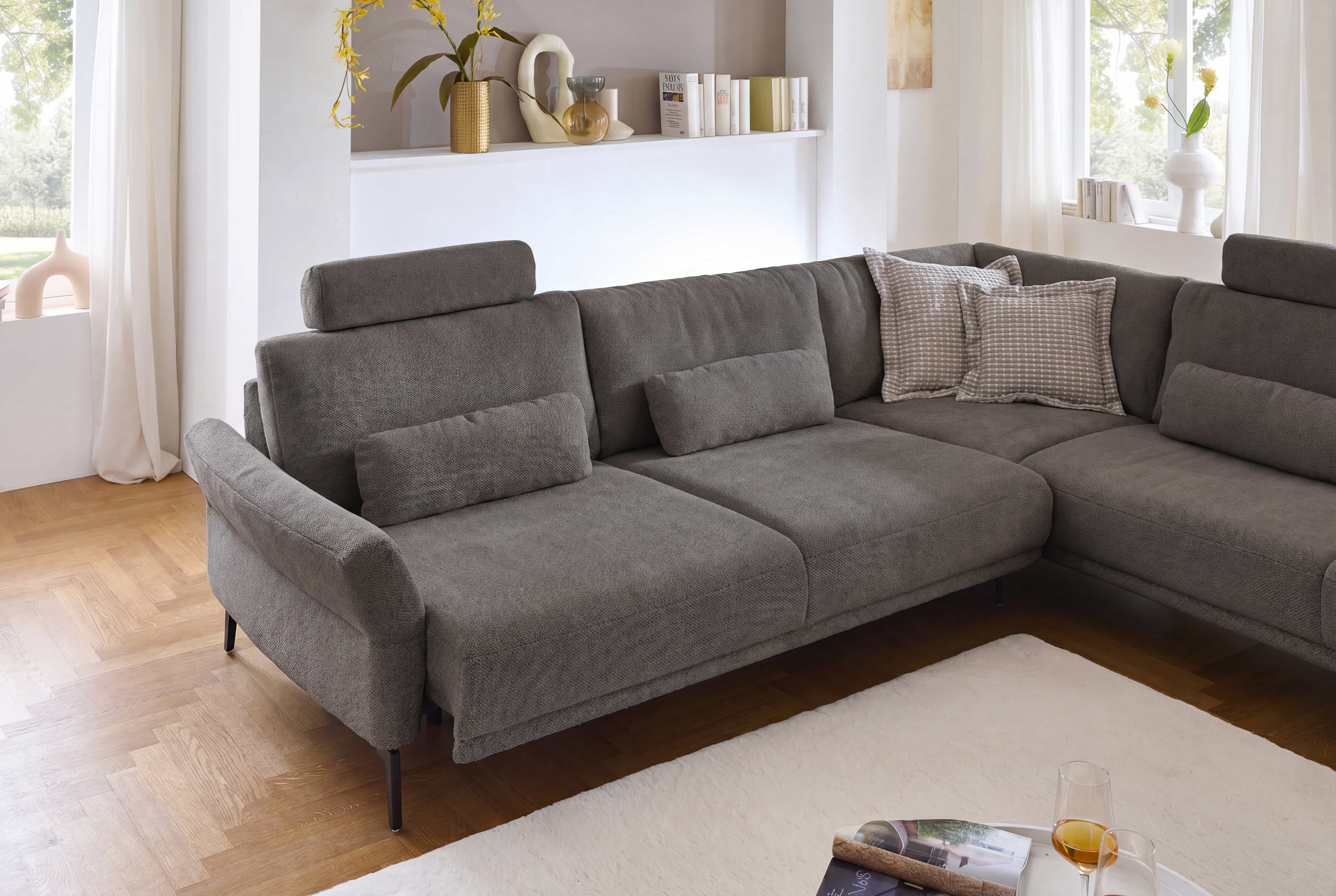Ecksofa Livio in L-Form mit grauem Stoffbezug, gepolsterter Rückenlehne und Kopfstützen