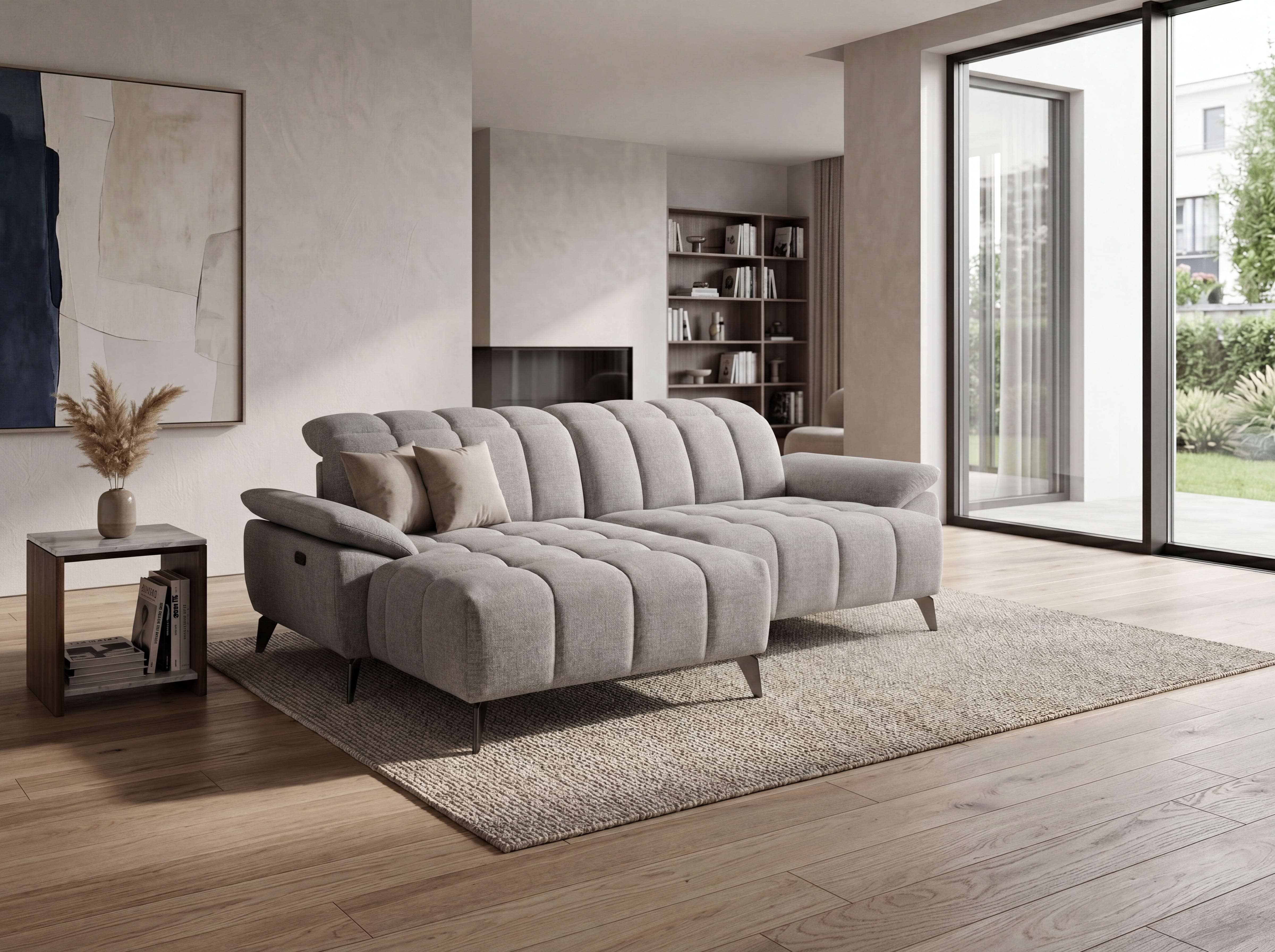 Ecksofa Modellname aus hellgrauem Stoff mit sichtbarer Steppung, niedrigen Armlehnen und Metallfüßen