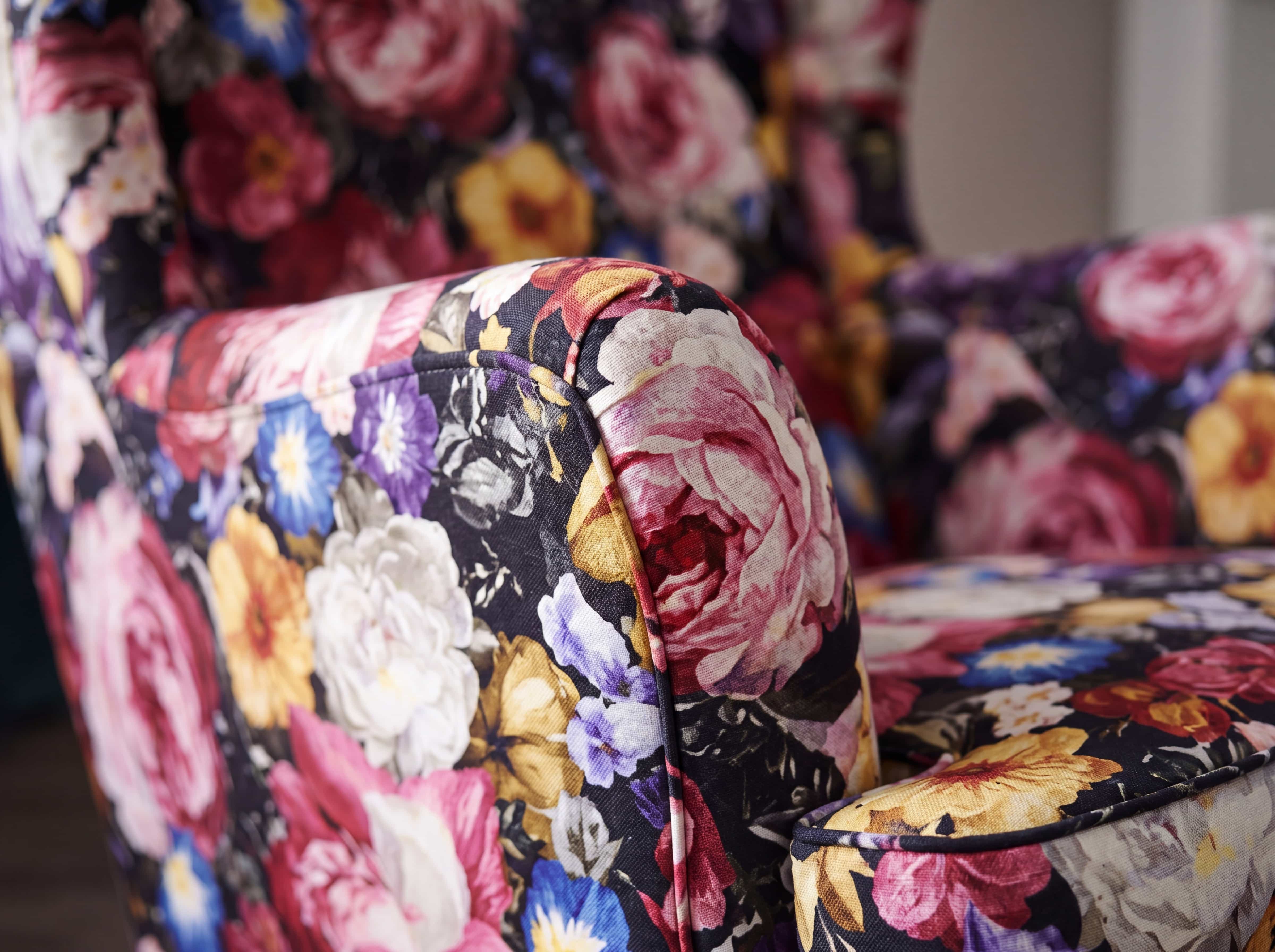 Ohrensessel mit floral gemustertem Stoffbezug in bunten Farben und gepolsterter Armlehne