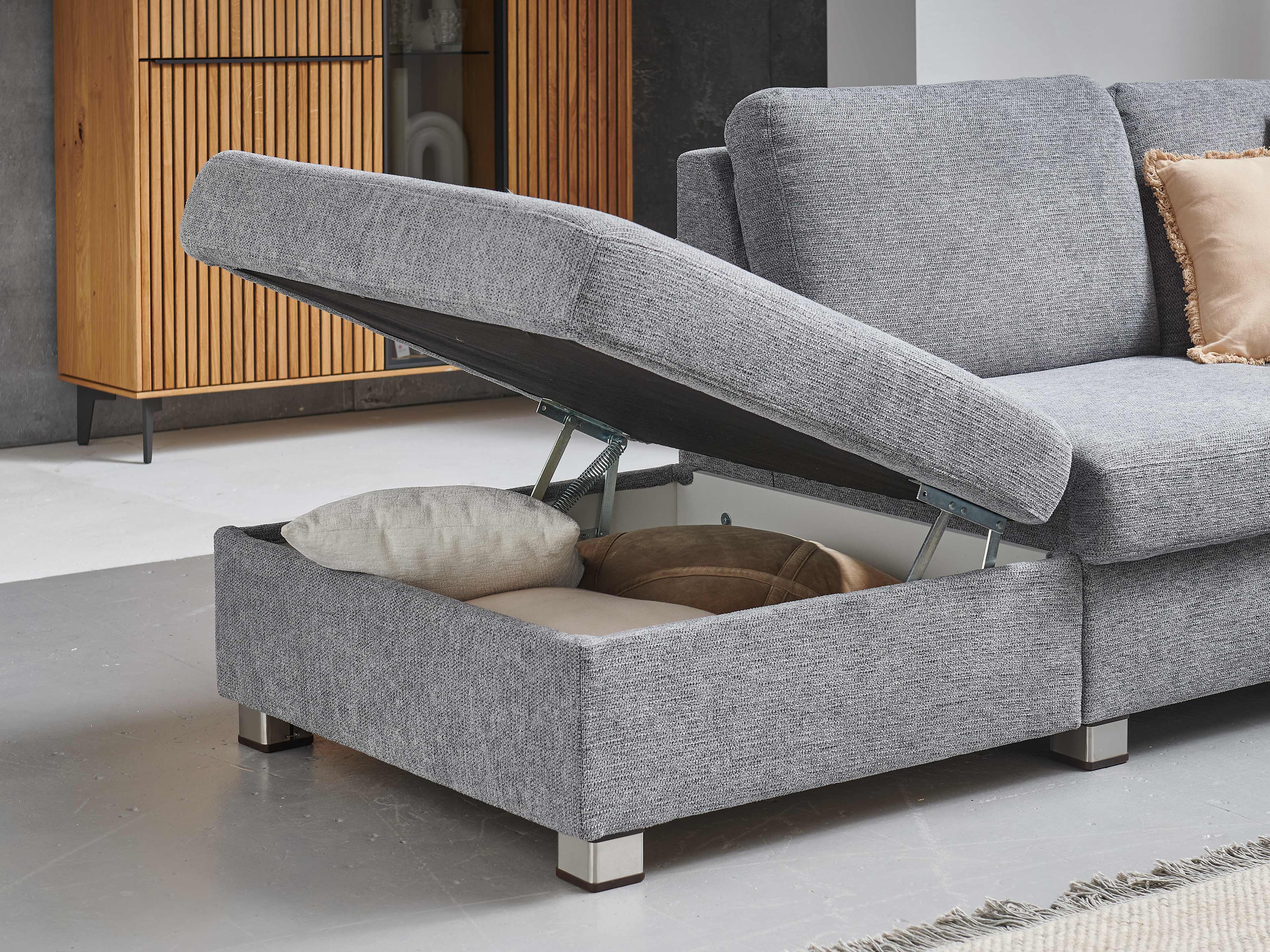 Ecksofa mit grauem Stoffbezug und integriertem, geöffnetem Stauraumfach auf Metallfüßen
