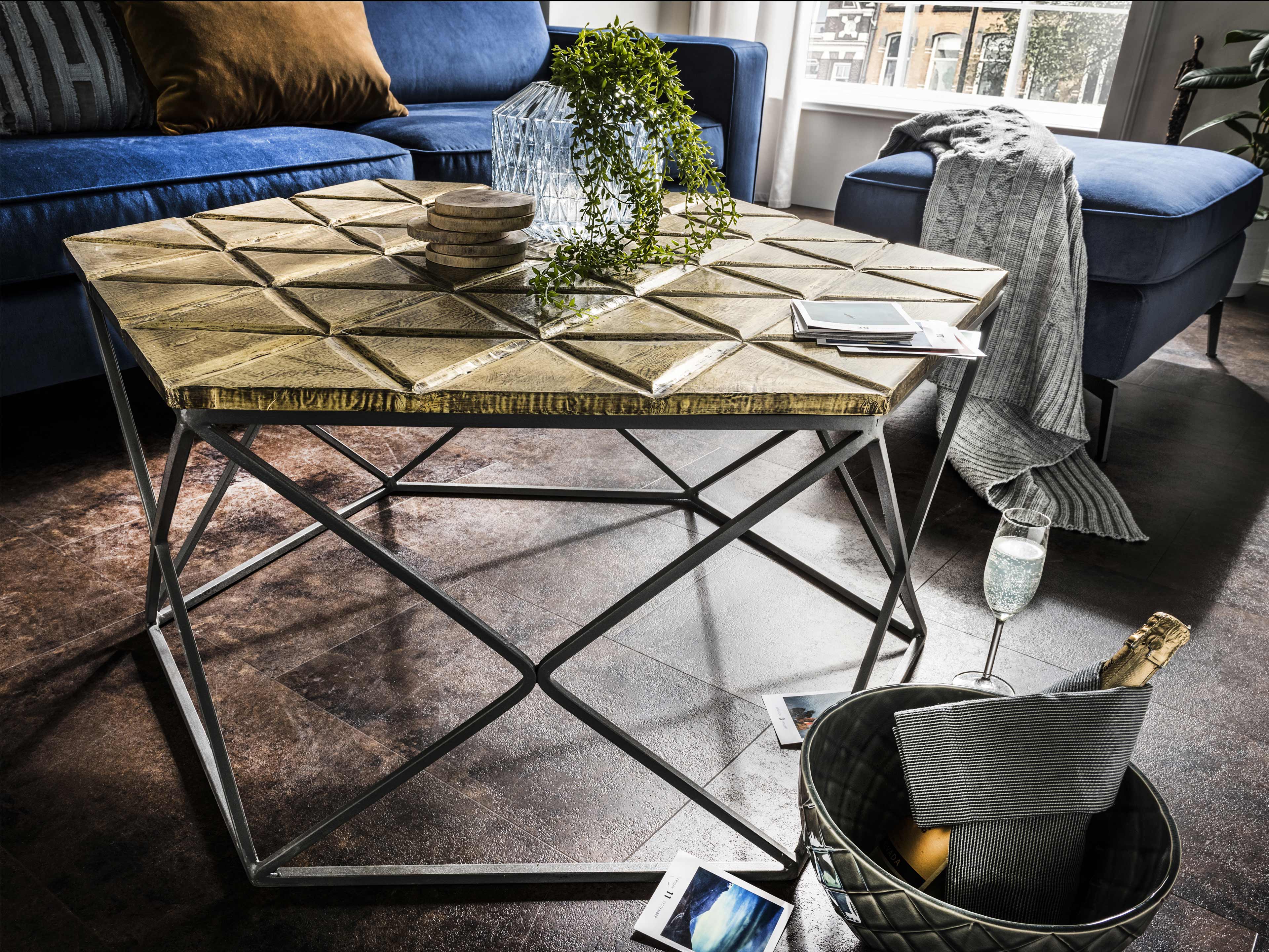 Couchtisch mit sechseckiger Holzplatte in natur und geometrischem Metallgestell in Schwarz.
