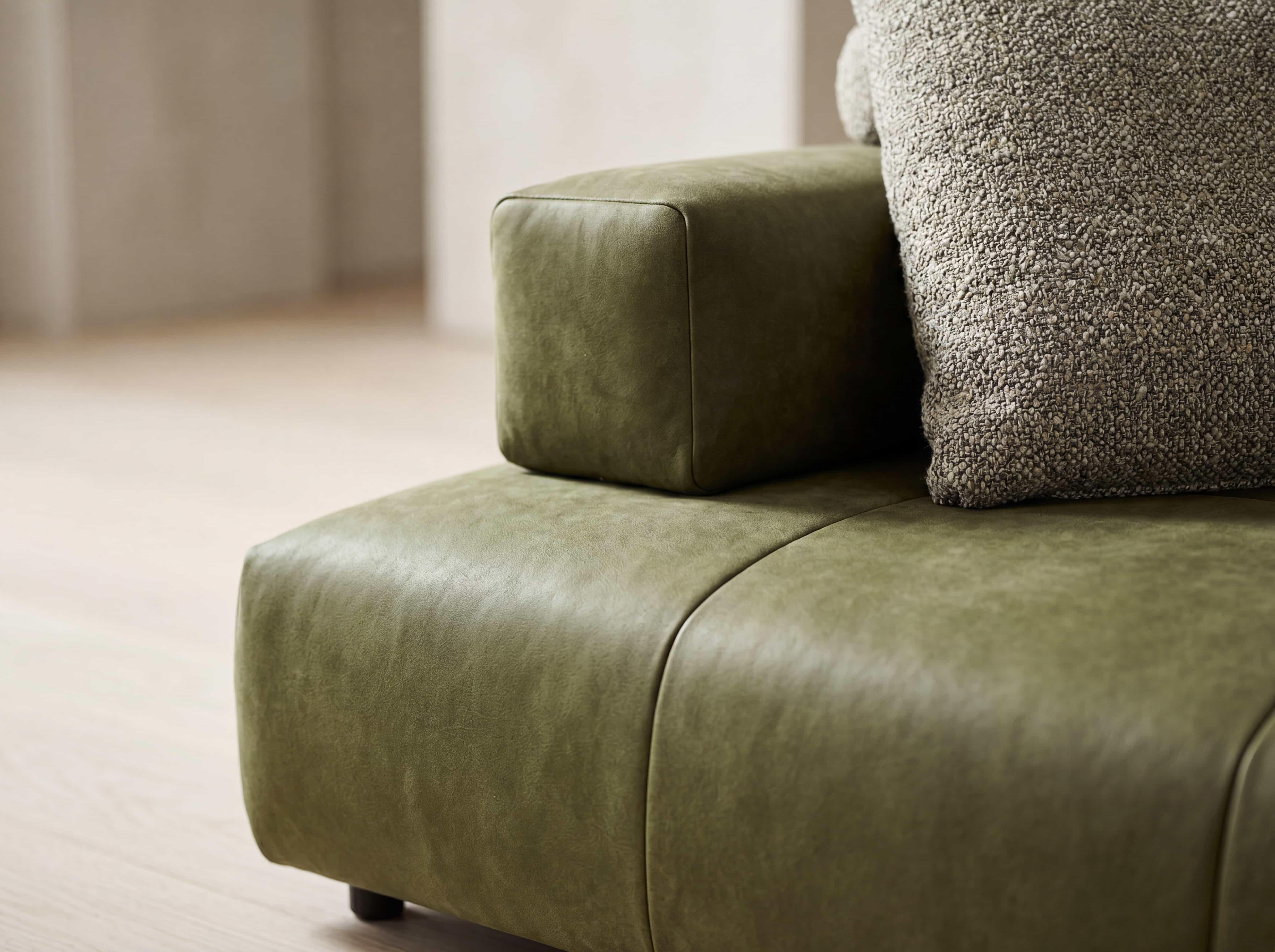 Ecksofa in Olivgrün mit Lederbezug, kubischer Armlehne und strukturiertem Dekokissen