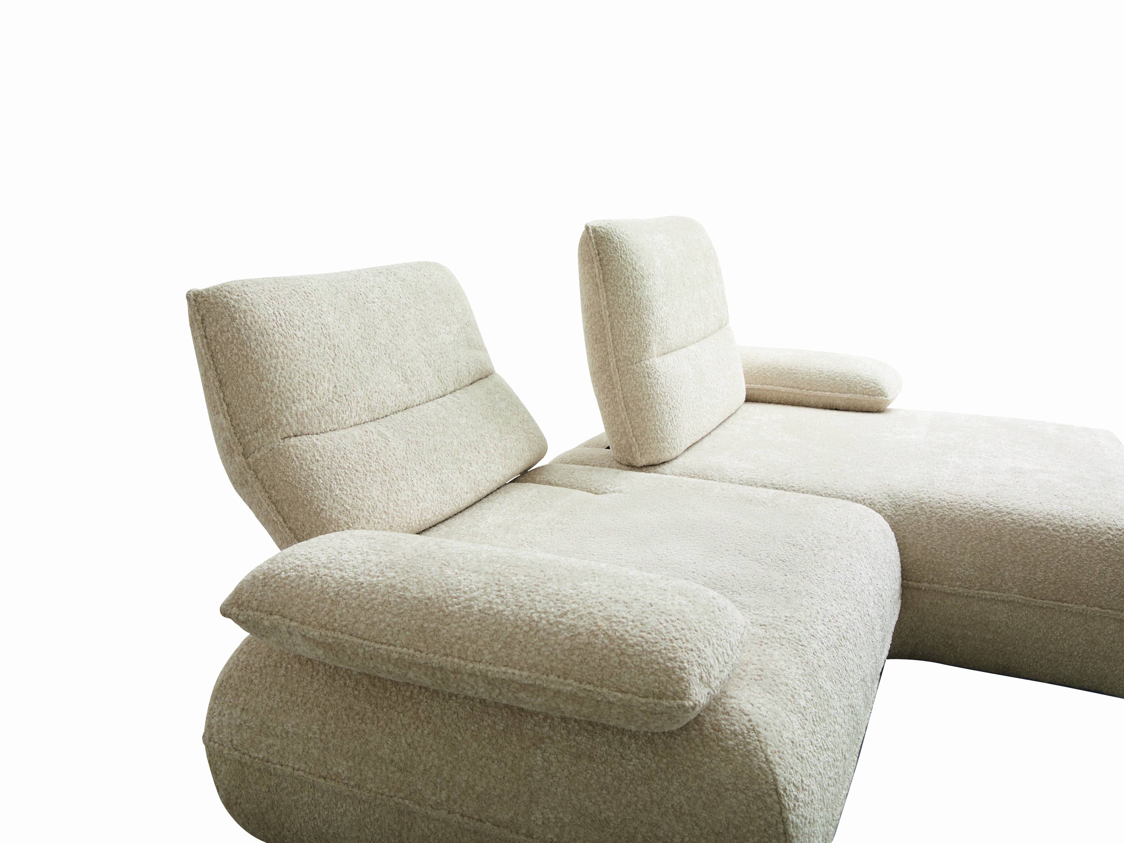 Ecksofa mit hellem, strukturiertem Stoffbezug, gepolsterten Rückenlehnen und breiten Armlehnen